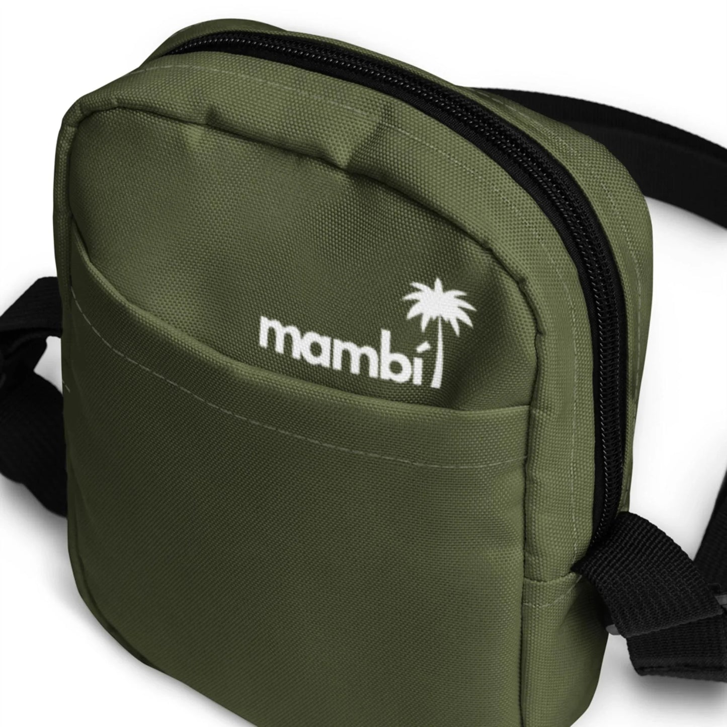 Close-up of a small olive green Mambí fabric bag with a front pocket, black zipper, and adjustable black strap. The word Mambí and a palm tree logo are printed in white on the front.