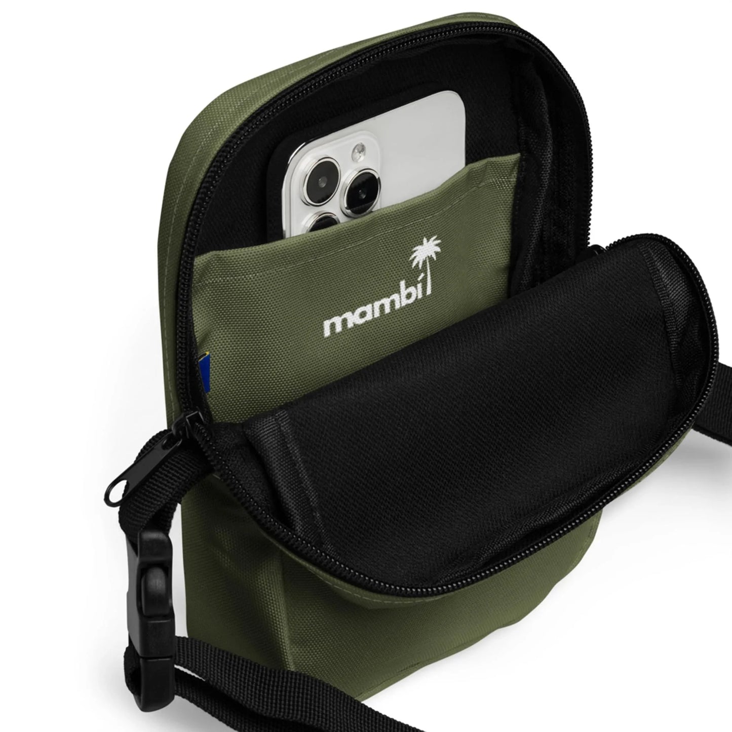 An olive green Mambí crossbody bag with a front pocket, partially unzipped to reveal a smartphone inside. The word mambi and a palm tree logo are printed in white above the pocket.