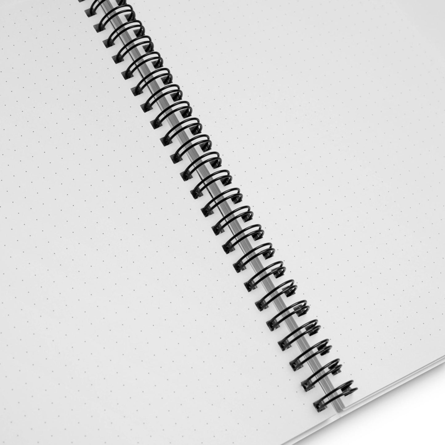An open spiral notebook with dotted pages is viewed from above. The metal spiral binding runs vertically down the center, and the pages are blank except for a subtle dot grid pattern.