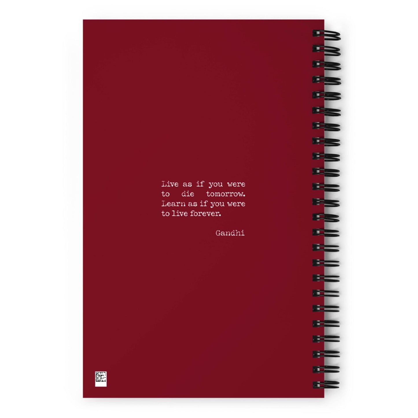 A maroon custom wire-bound notebook with dotted pages, featuring a centered white quote: Live as if you were to die tomorrow. Learn as if you were to live forever. - Gandhi. The background is plain with no other designs.