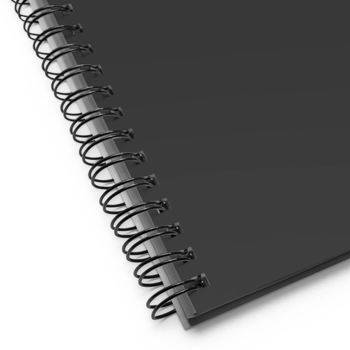 Close-up of a black custom wire-bound notebook positioned at an angle on a white surface, showing the wire binding and the edge of the cover.