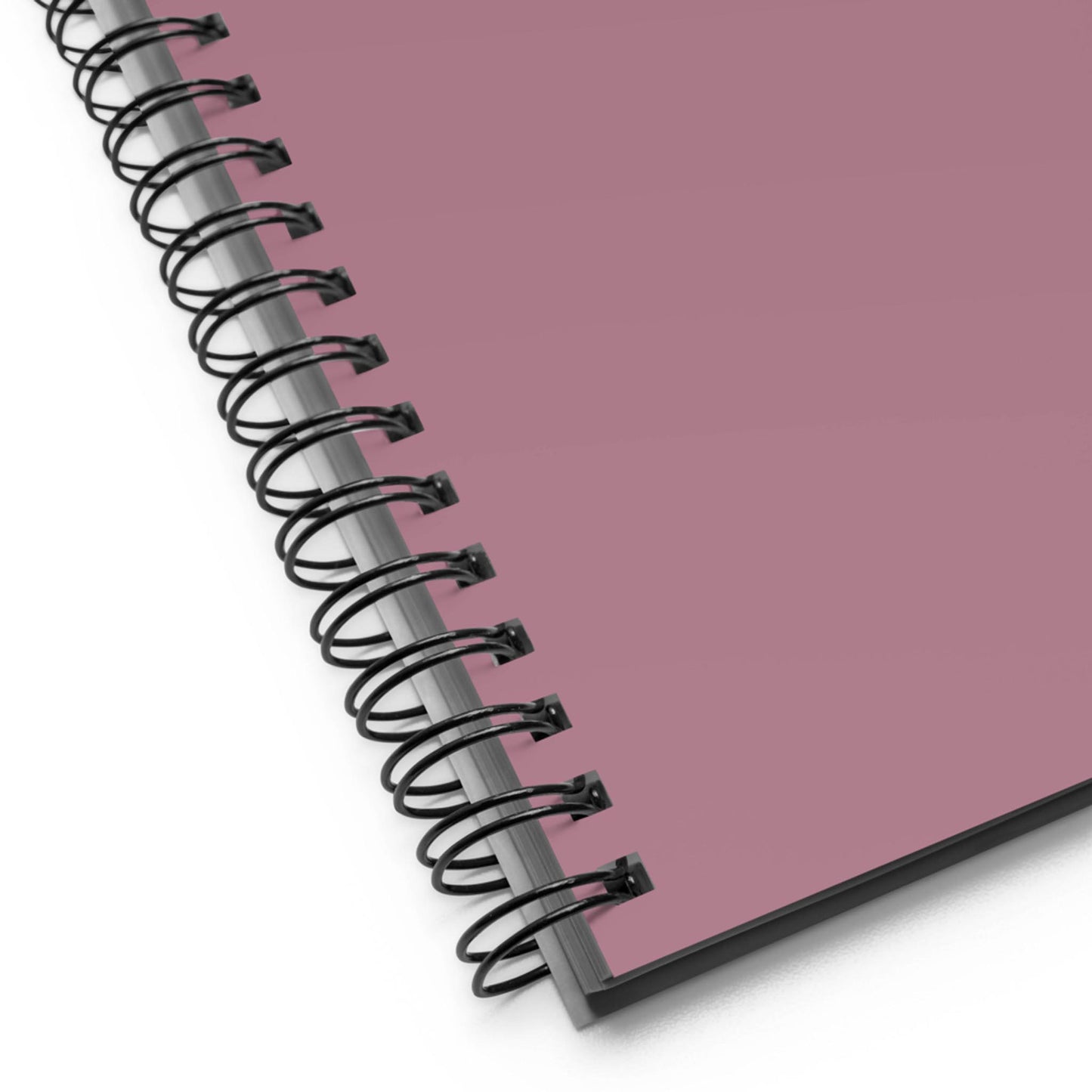 A close-up of a custom wire-bound notebook with a mauve-colored cover, showing the black metal coil binding along the left edge and the slightly textured surface of this stylish daily companion notebook.