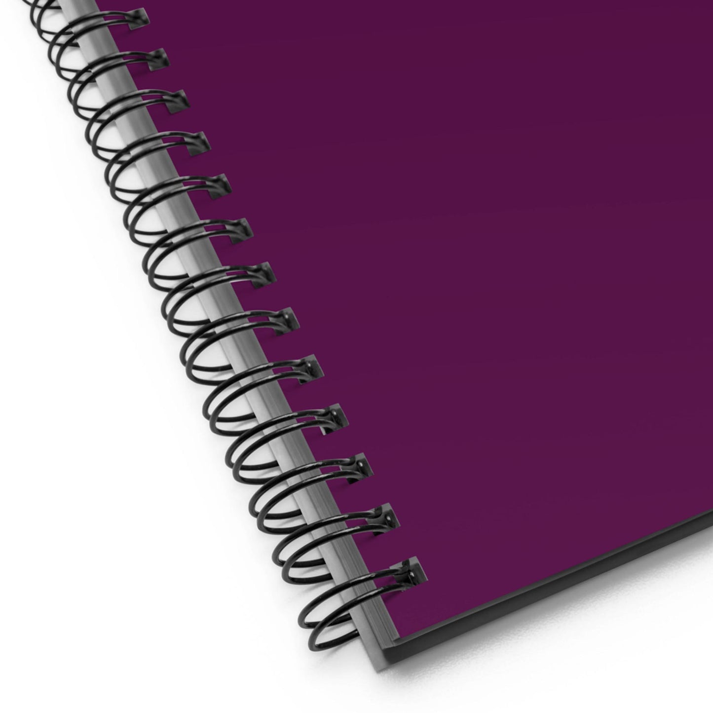 Close-up of a wire-bound notebook with a dark purple cover, shown at an angle on a white background.