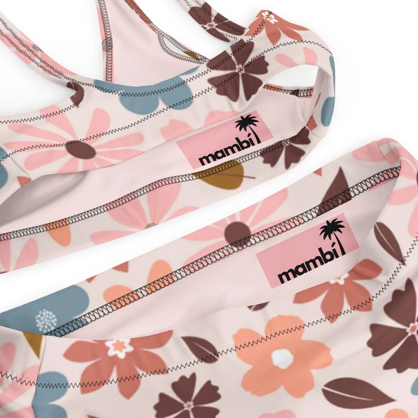 Close-up of pink and white floral-patterned Mambí sports bras, featuring a black palm tree logo on a pink background.