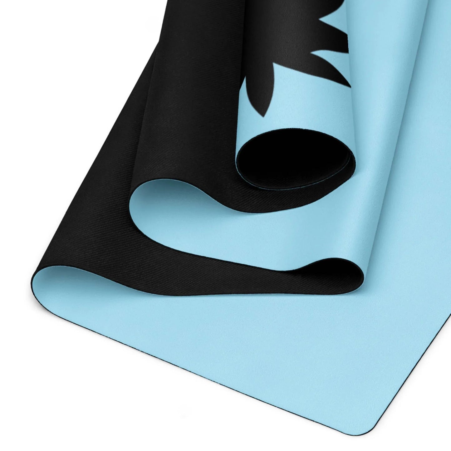 A close-up view of a Mambí yoga mat with a light blue top and black underside, partially rolled to display both colors and a black abstract design on the blue surface.