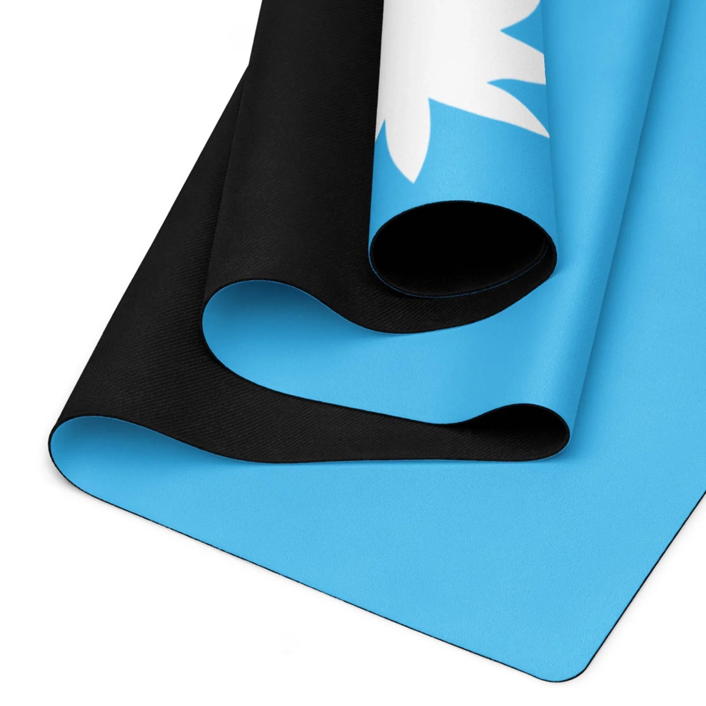 A close-up of a rolled-up Mambí yoga mat, featuring a black underside and a blue top surface with a partial white floral or leaf design.