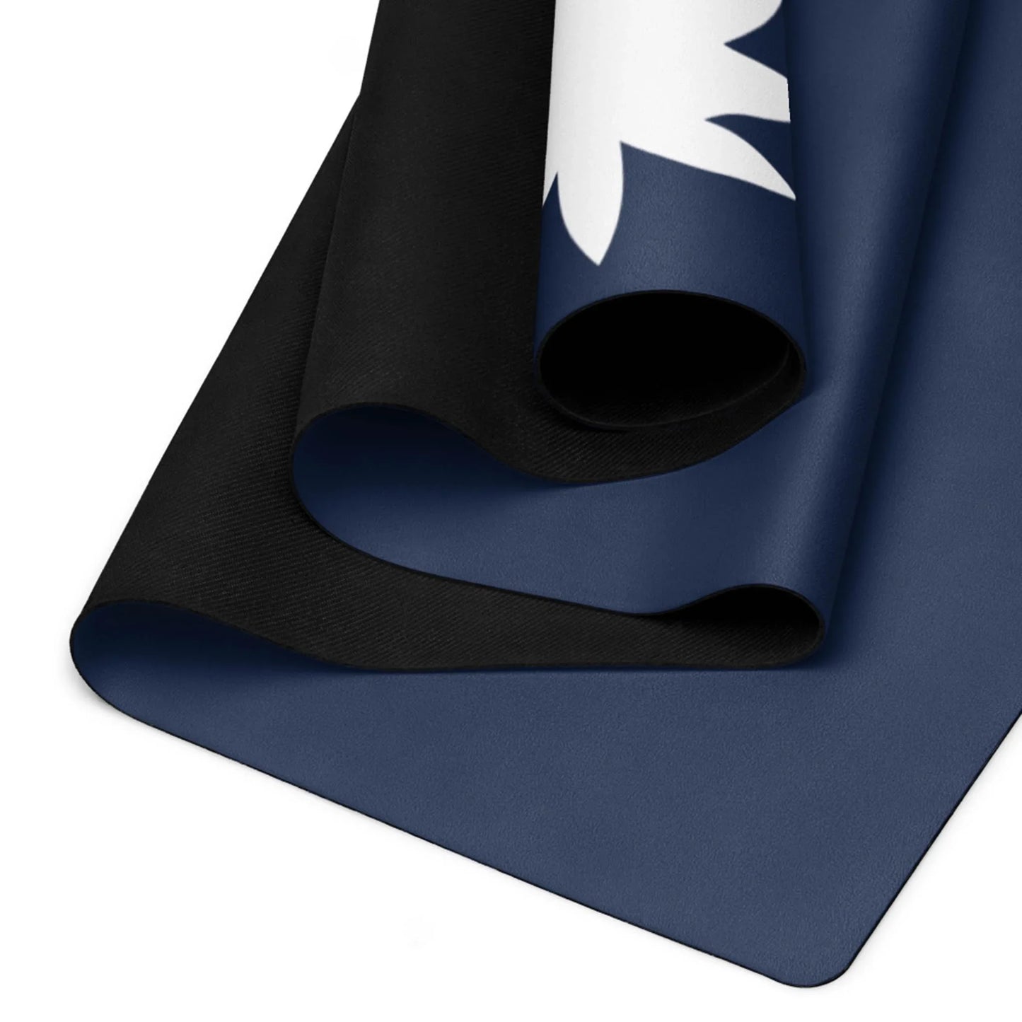A close-up of two rolled Mambí yoga mats, one black and one dark blue with a white leaf design, partially overlapping on a flat surface.