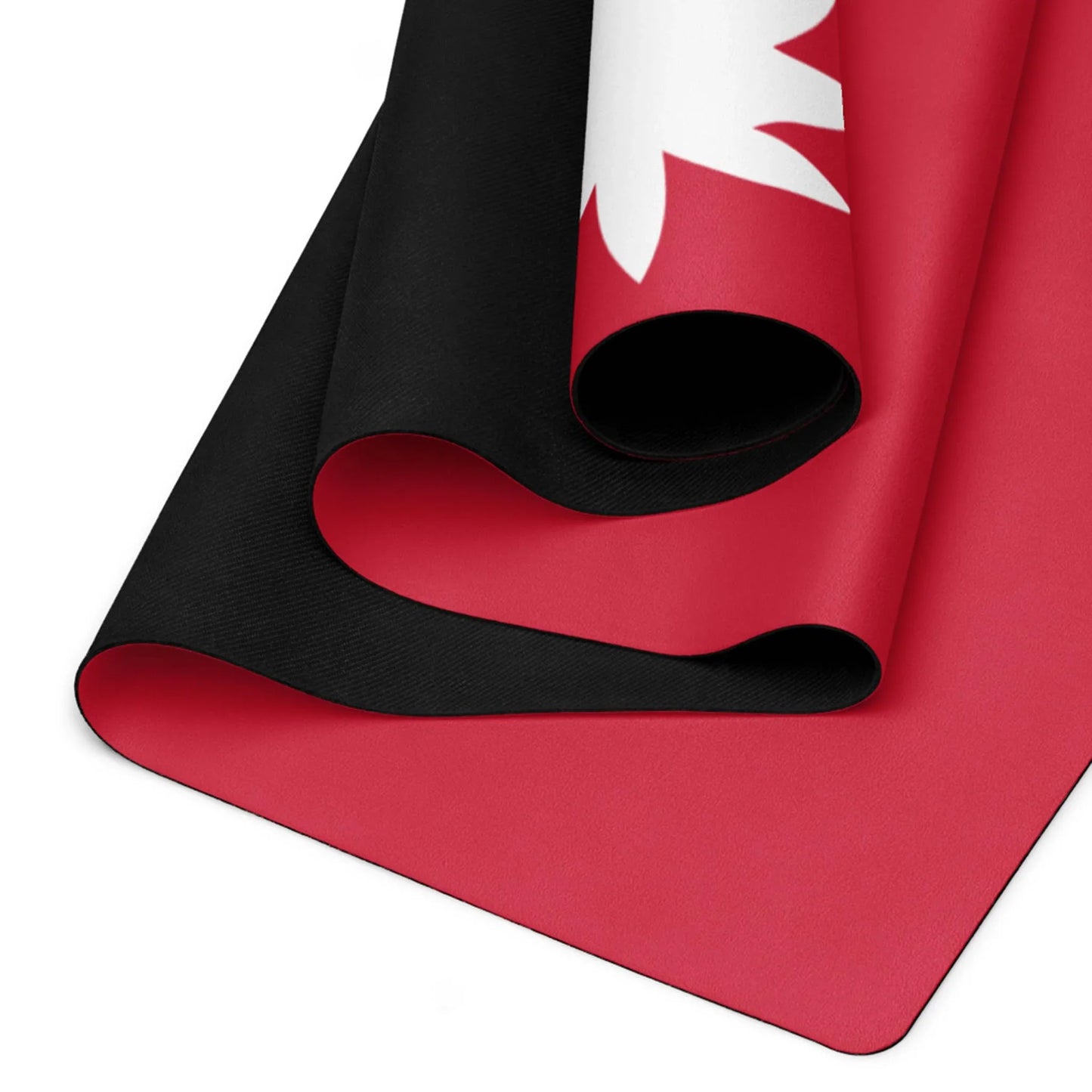 A close-up of three rolled yoga mats stacked together, featuring bold black and red colors with part of a Mambí-inspired white leaf or maple design visible on the top mat.
