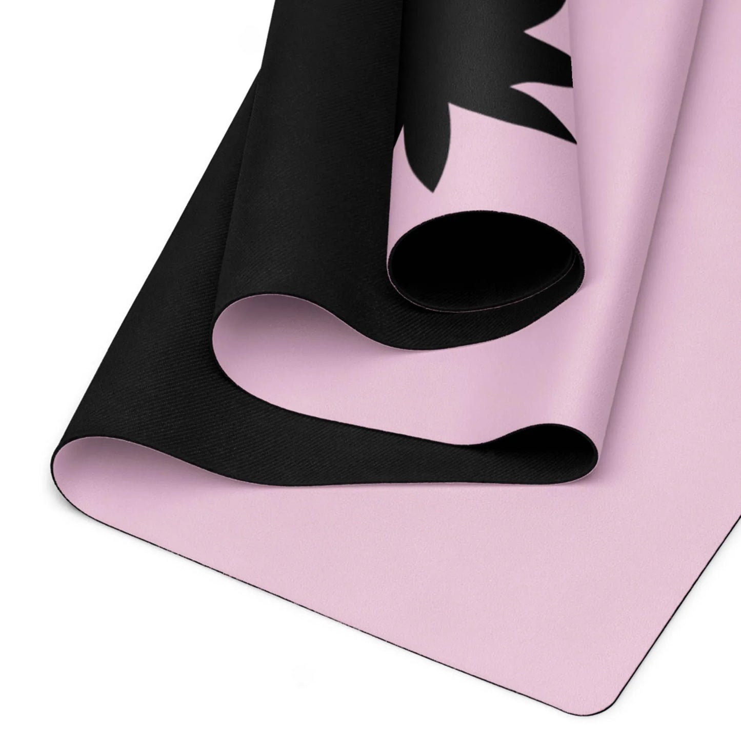 A close-up view of a Mambí yoga mat with a soft pink surface and black design accents, highlighting the layered texture and curved edges.