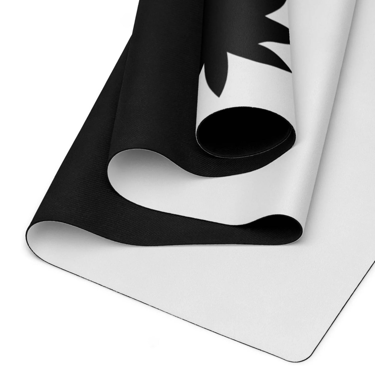 Close-up of two overlapping, unrolled Mambí yoga mats with a black and white design. The mats rest on a white surface, highlighting their smooth and slightly textured material.