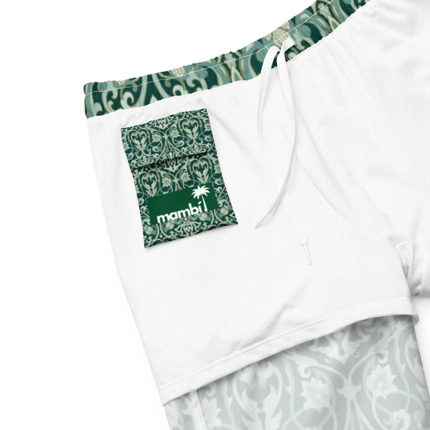 The Oz Swim Trunks by Printful are mens white athletic shorts with a green ornate waistband and lining, four-way stretch water-repellent fabric, and a green pocket featuring a white palm tree logo with mambi.