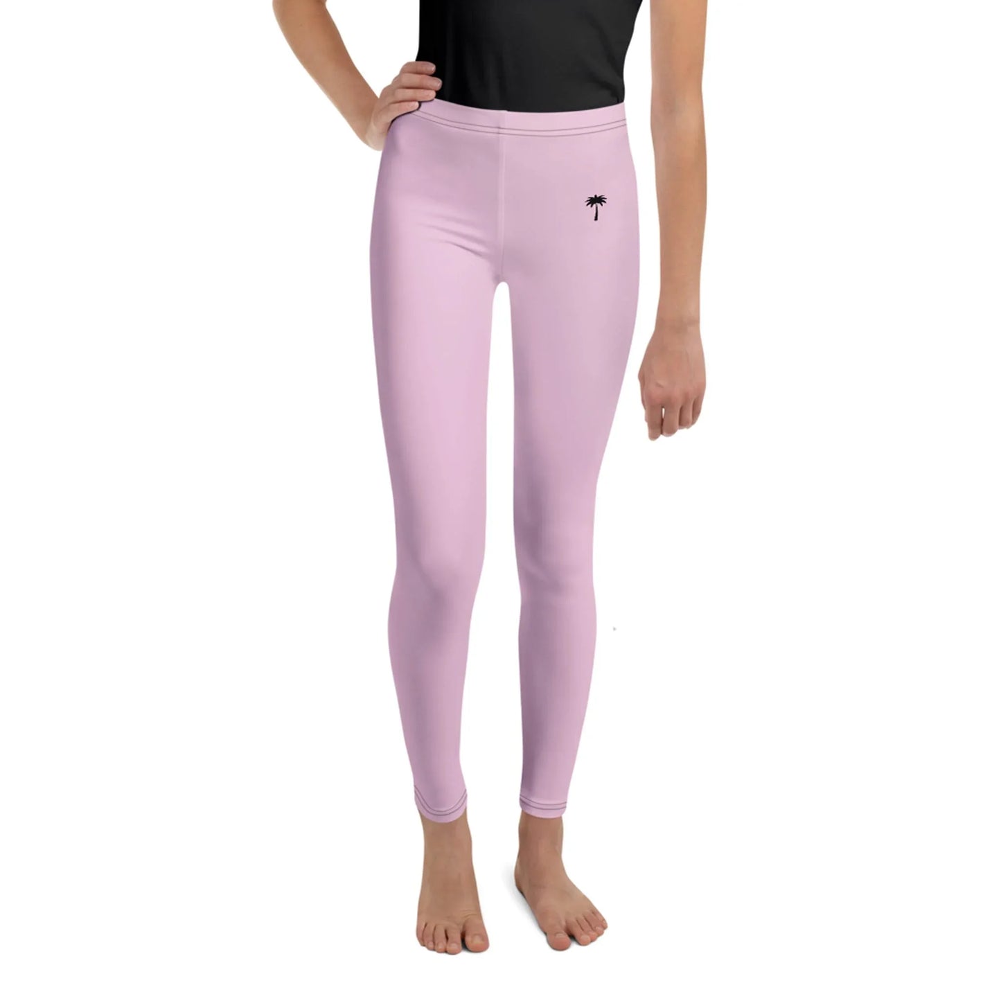 Person wearing high-waisted, light pink Mambí leggings with a small black palm tree design near the left hip, standing barefoot against a white background. Only the lower half of the body is visible.