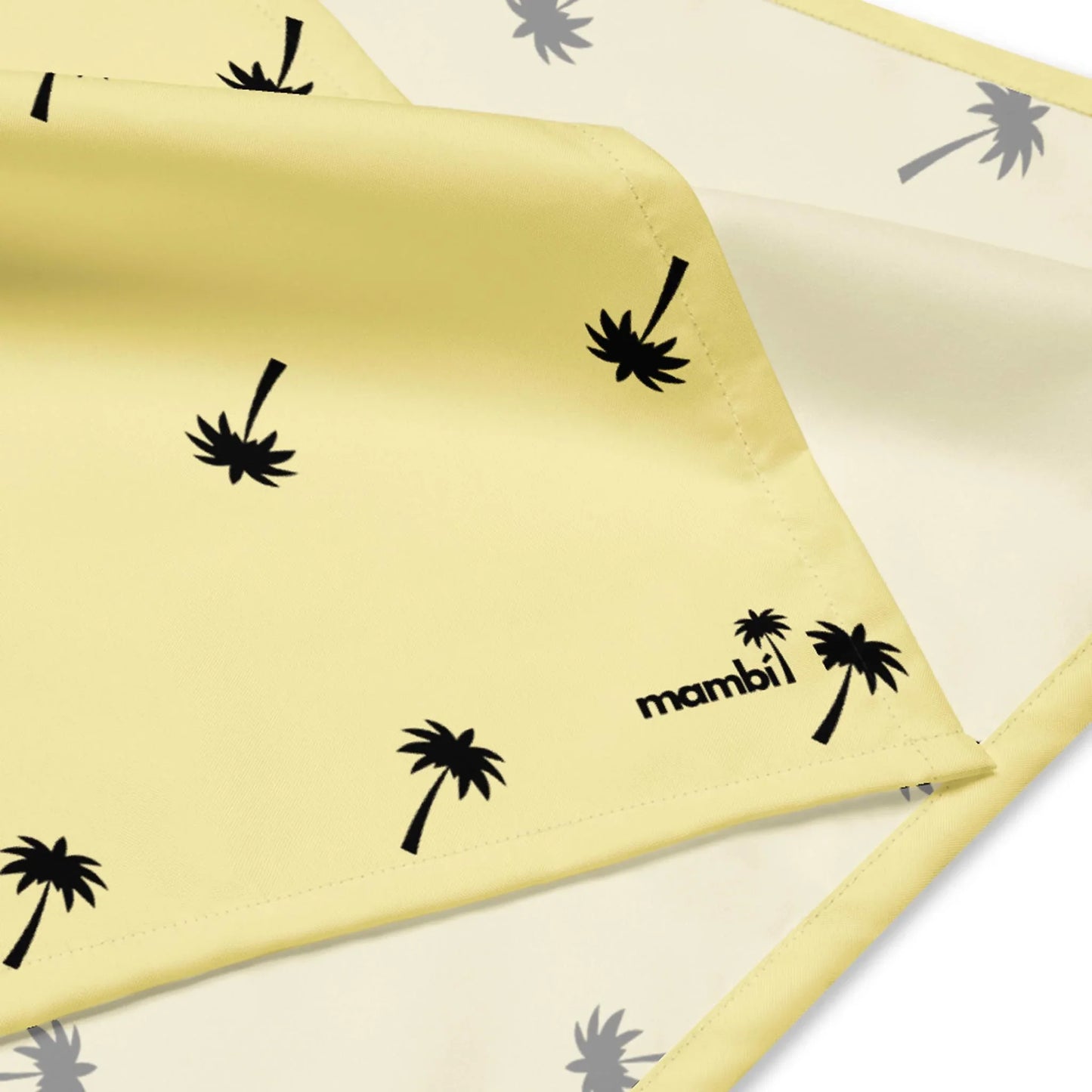 A yellow fabric with small black palm tree prints and Mambí in black text on one corner. The neatly folded fabric displays both sides.