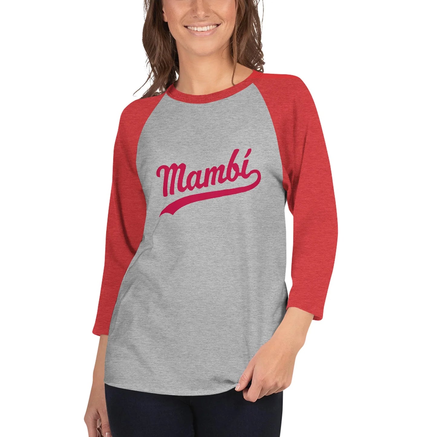 A woman smiles in a grey and red raglan-sleeve shirt featuring Mambí in bold red script on the front, her hand resting at her side.
