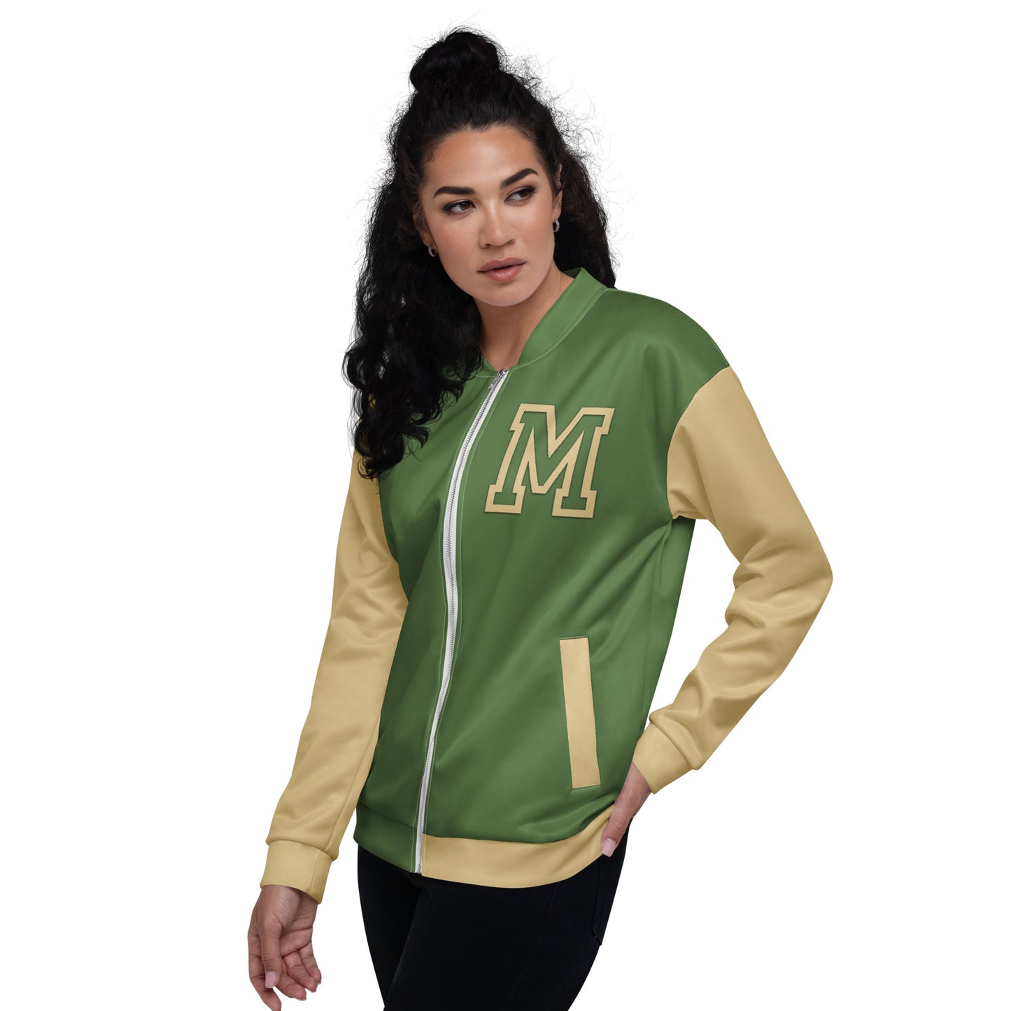 Woman with long curly dark hair wears a green and yellow varsity bomber jacket with an M on the chest, posing with one hand in her pocket against a plain white background.