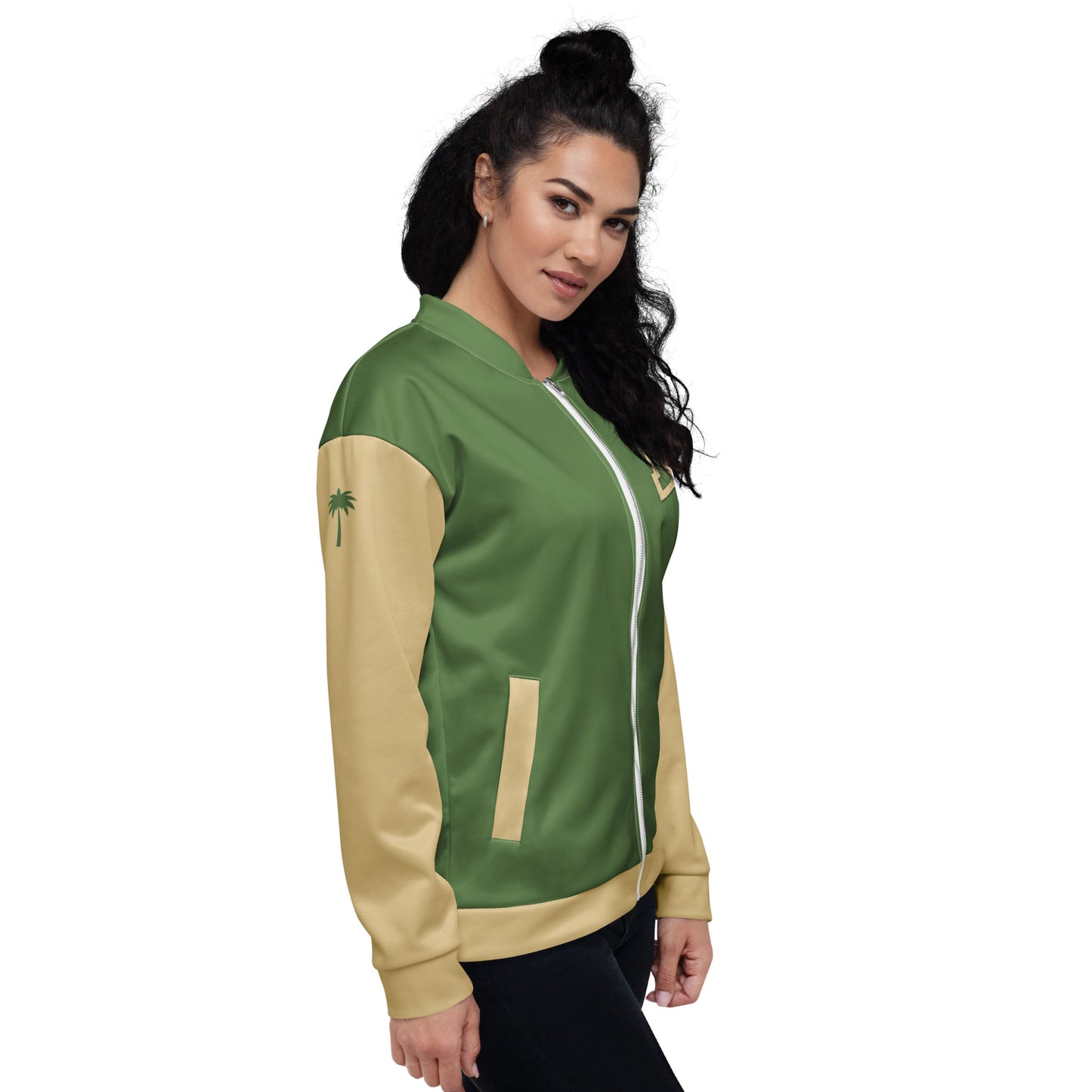 Woman with long, dark, curly hair wearing a green and beige varsity bomber jacket with premium stitching, a white zipper, and beige sleeves featuring a small palm tree graphic, standing and smiling slightly.