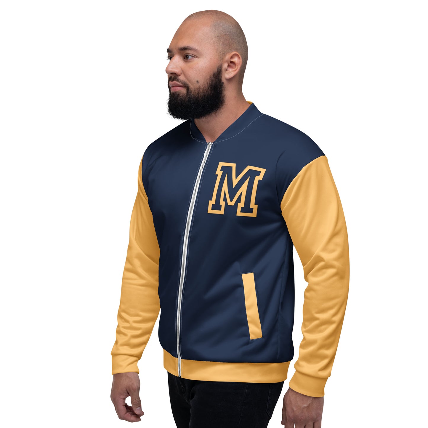 A man with a beard wears a navy and yellow letterman jacket, featuring premium stitching and a large yellow M on the chest. Yellow accents highlight the pockets and sleeves as he stands looking slightly to the left.