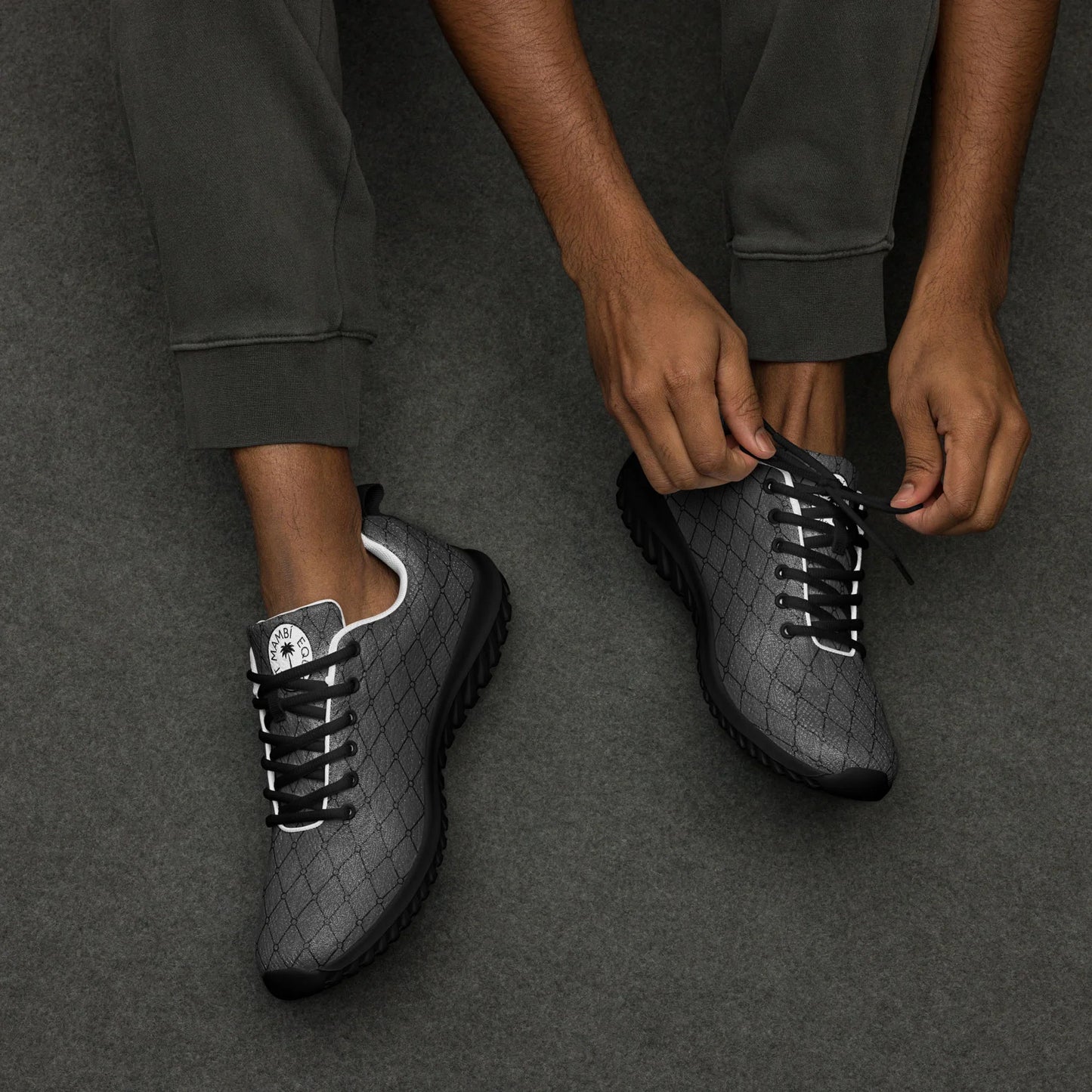 Man tying black geometric pattern Mercury men's athletic shoes on gray background
