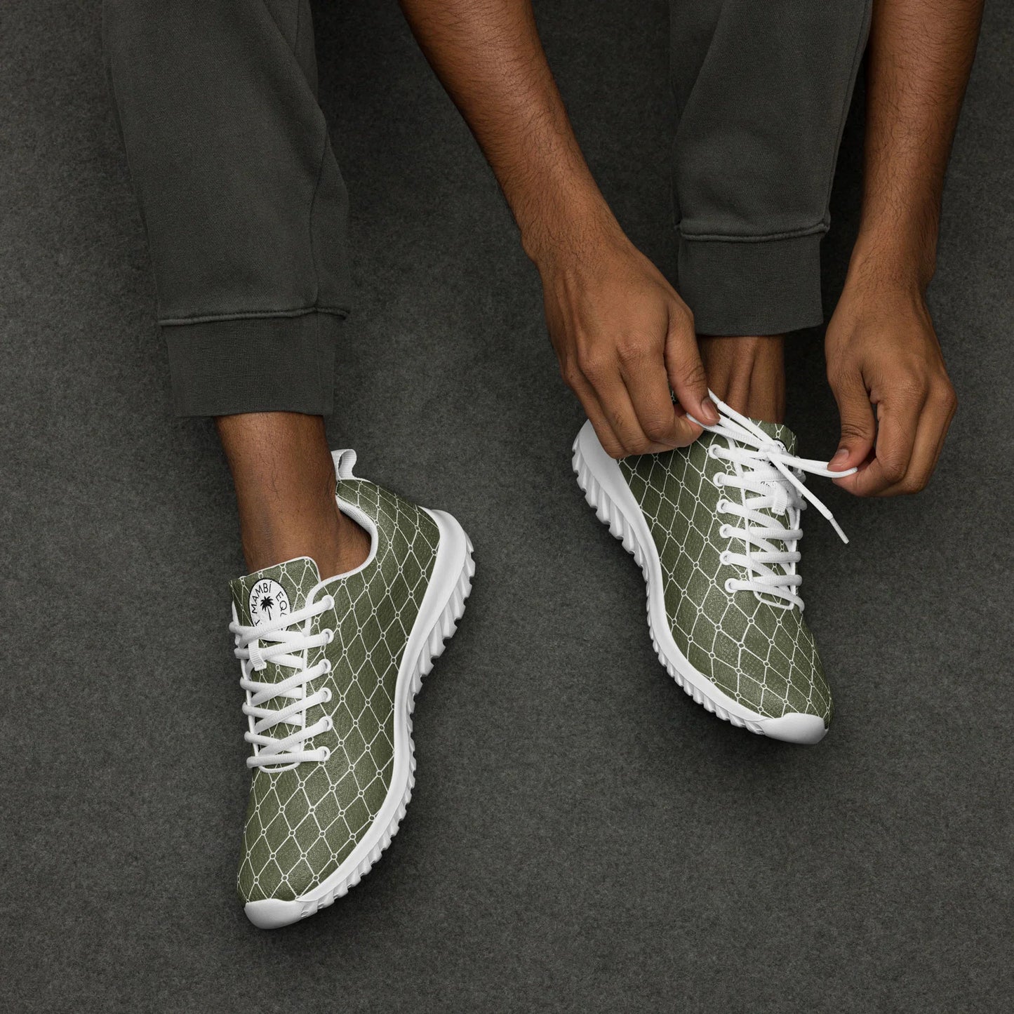 Man tying laces on green men's athletic shoes with white geometric pattern on gray background