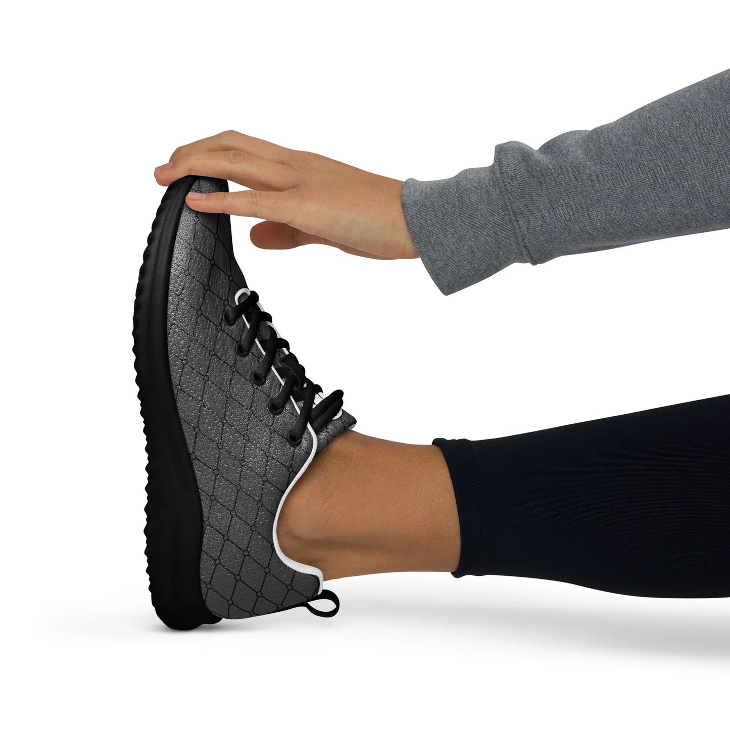 Woman stretching in black quilted athletic shoe with black sole on white background