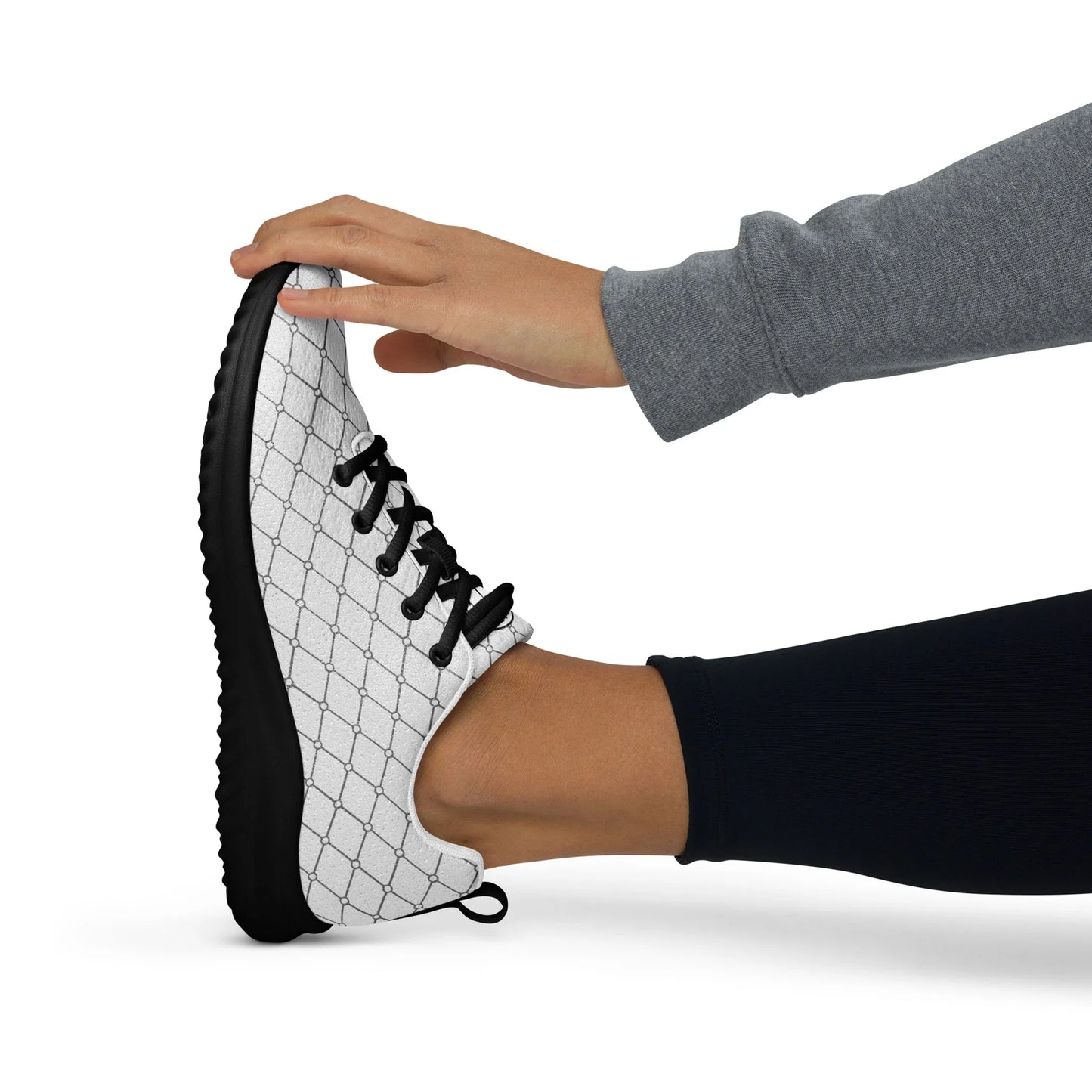 Woman stretching in white athletic shoe with black laces and geometric pattern