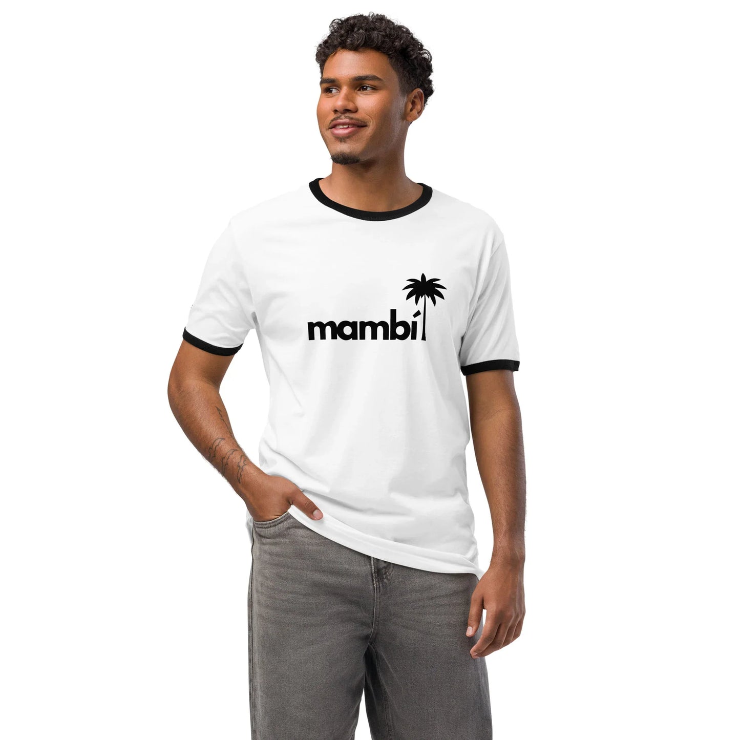 A man wearing a relaxed fit white ringer t-shirt with black trim and the word mambi plus a palm tree graphic on the front, standing with one hand in his pocket and smiling for a retro look.