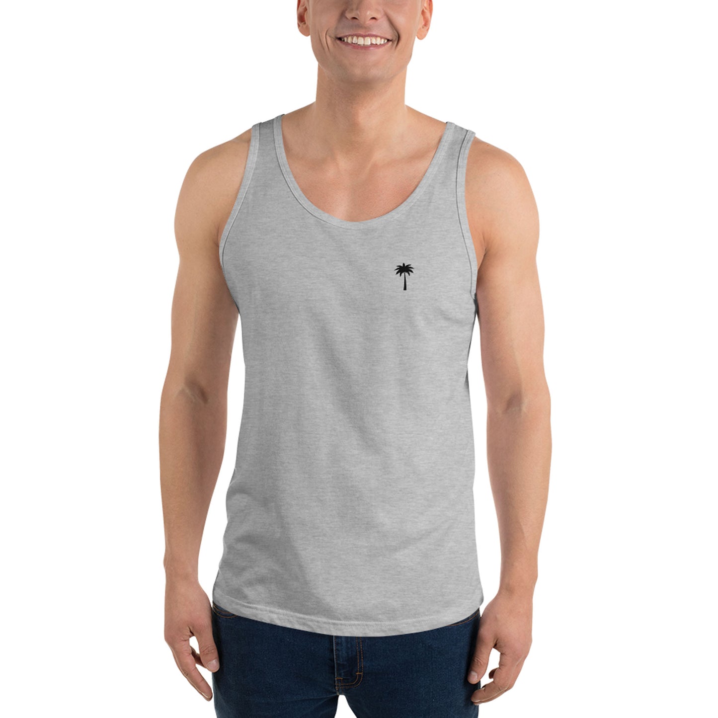 A smiling man wears a classic style light gray sleeveless tank top with a small black palm tree logo on the left chest, crafted from premium materials, paired with dark blue jeans and standing against a plain white background.