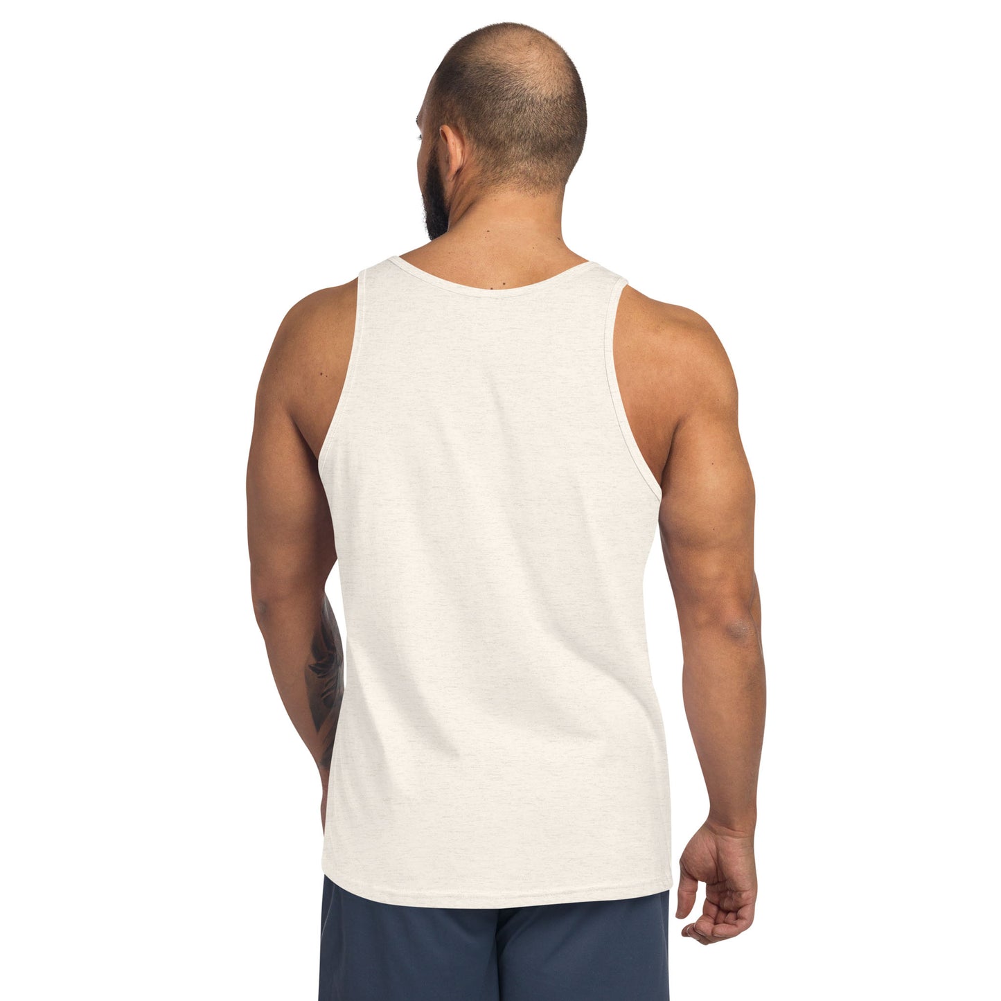 A man with a shaved head and beard is shown from behind, wearing a classic style sleeveless white tank top and dark shorts. His right arm has a visible tattoo. He is standing against a plain white background.