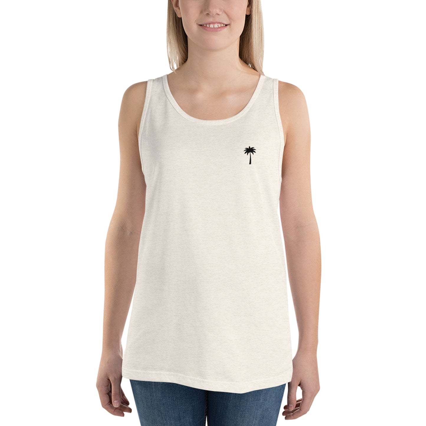 A person wearing a classic style, sleeveless white tank top with a small black palm tree graphic on the left chest, paired with blue jeans, stands against a plain white background.