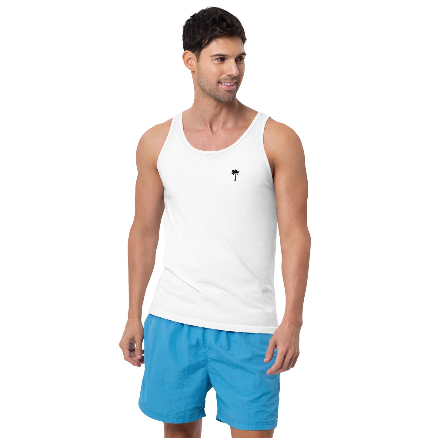 A man wearing a classic style tank top with a small palm tree graphic on the chest and blue shorts stands facing slightly right, smiling.