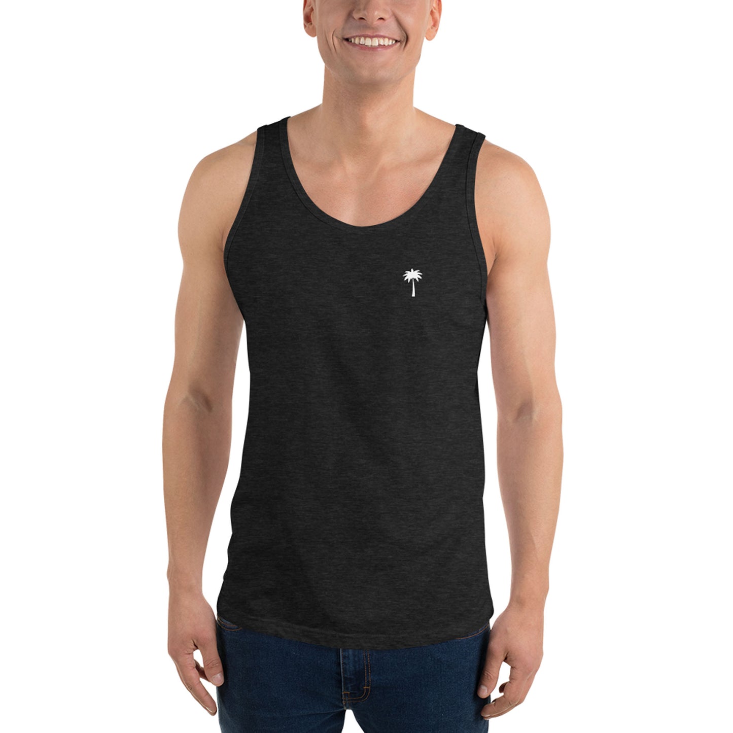 A man wearing a classic style black sleeveless tank top with a small white palm tree graphic on the left chest stands smiling with his arms relaxed at his sides. He is wearing blue jeans.
