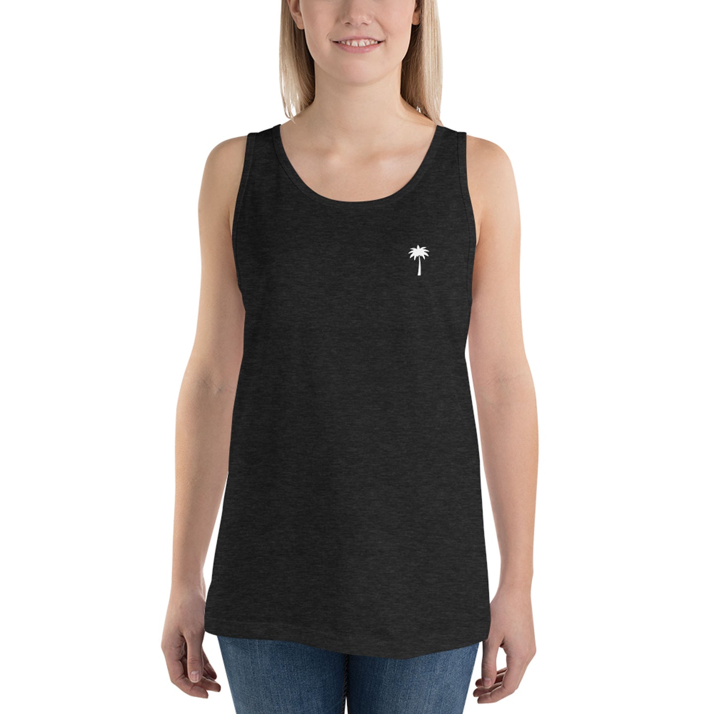 A smiling person wearing a sleeveless black tank top made from premium materials, featuring a small white palm tree graphic on the left chest, paired with blue jeans, standing against a plain white background.