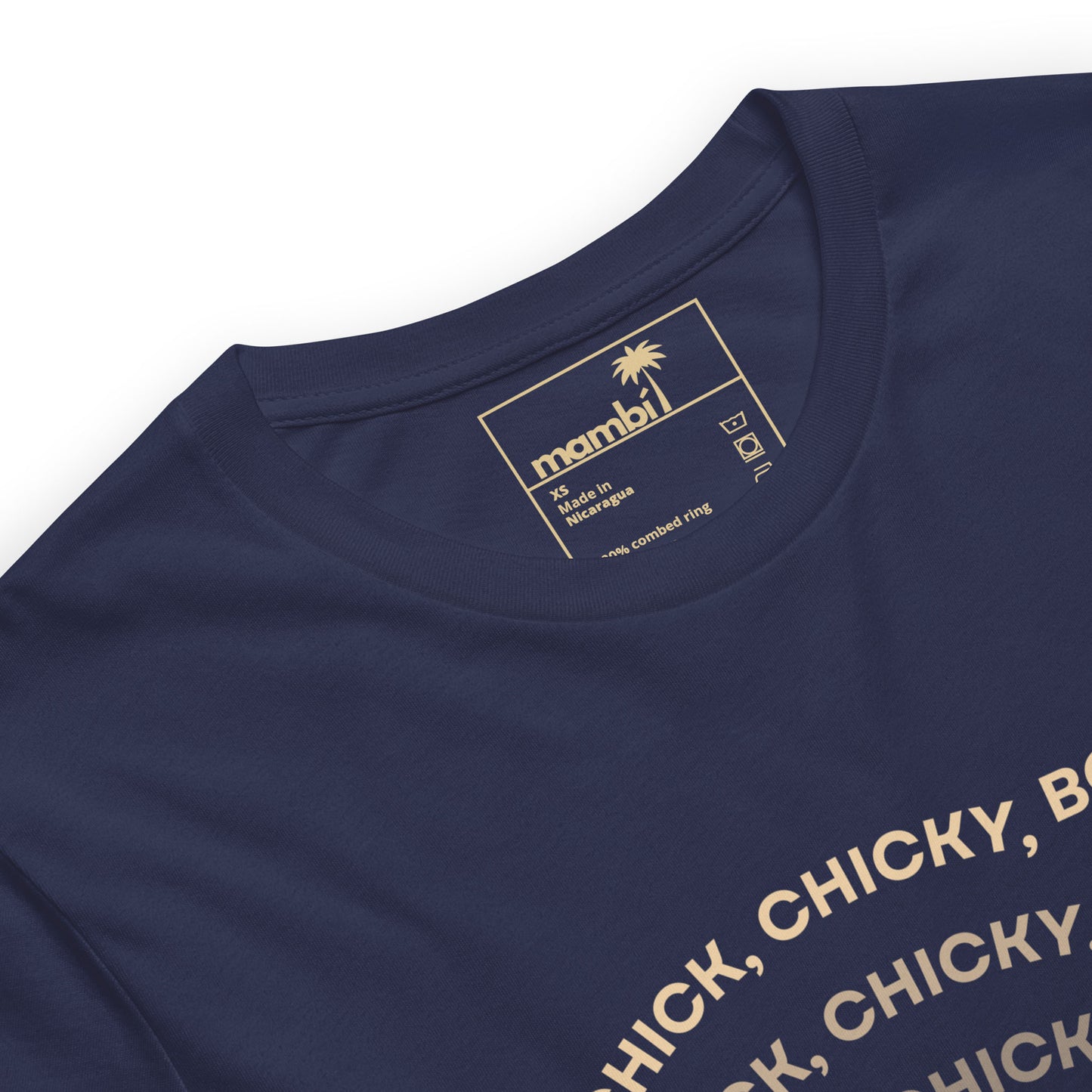 A navy blue fitted shirt crafted from comfortable cotton, featuring a gold printed neck label with mambi branding, size, care instructions, a palm tree icon, and website link. Part of the graphic tee’s beige printed text is visible on the front.
