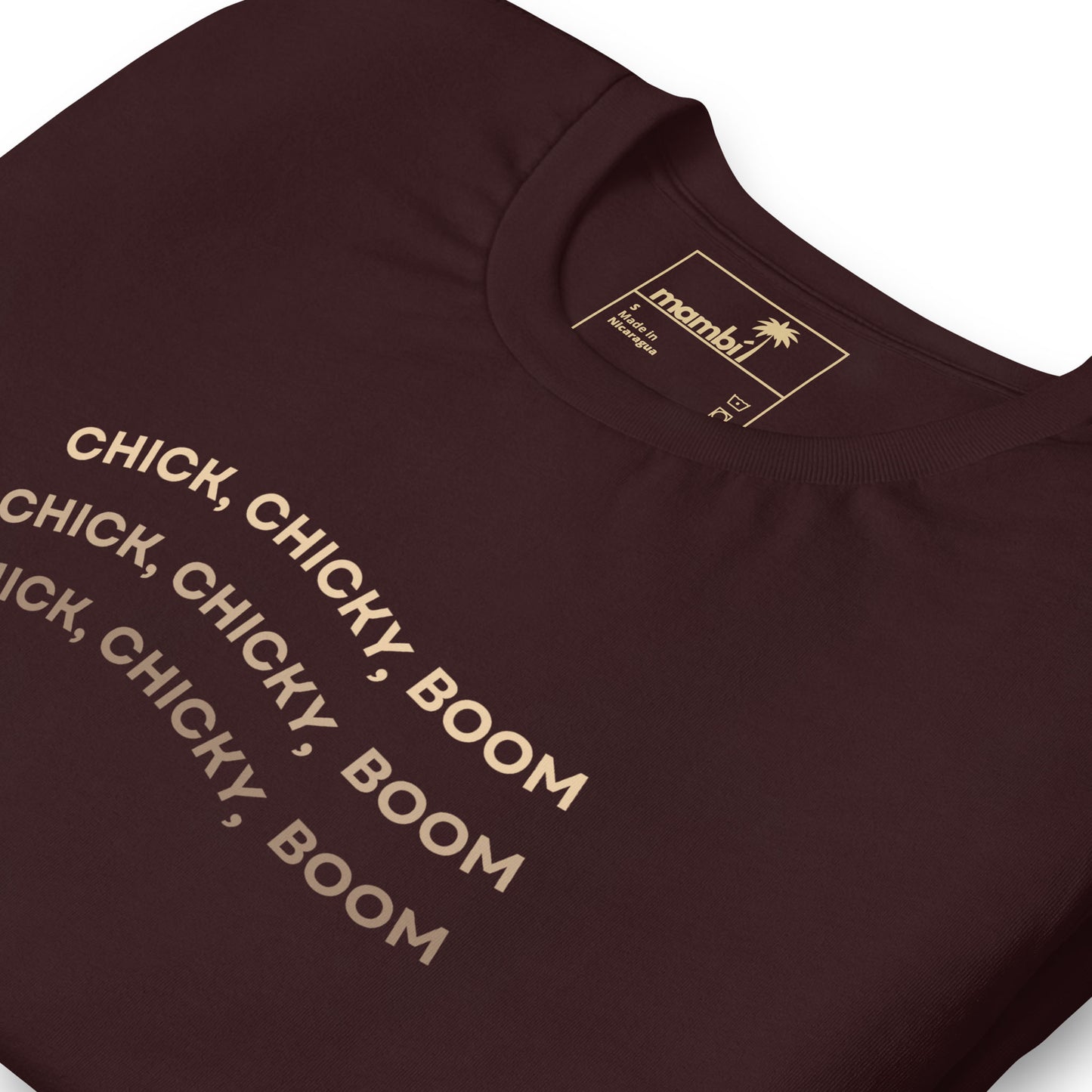 A maroon fitted shirt with the text CHICK, CHICKY, BOOM repeated three times in bold, beige letters. This comfortable cotton tee from Manby features graphic tees style and includes care information on the label.