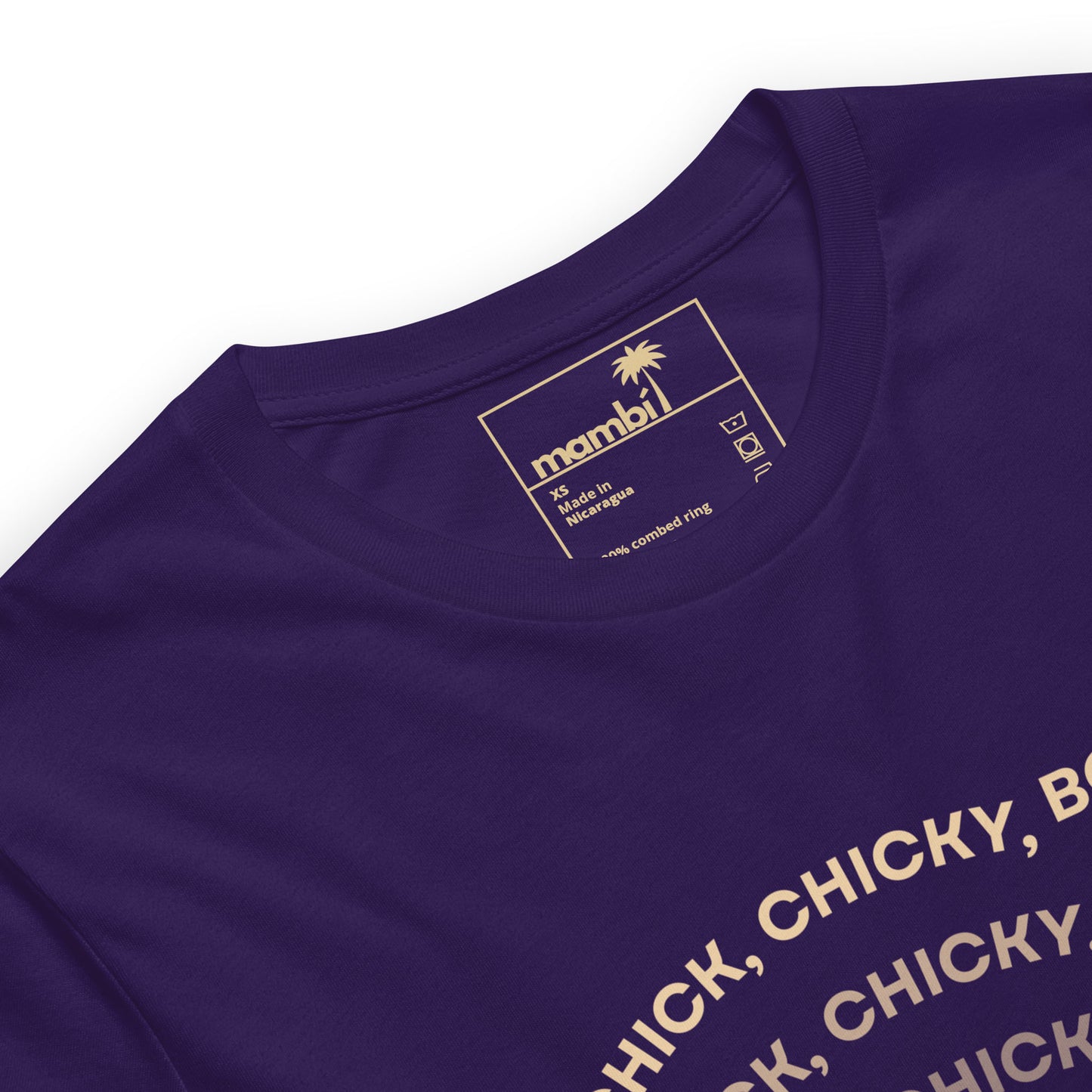 Close-up of a purple graphic tee made from comfortable cotton, featuring a beige inner label with “mambi,” washing symbols, and a palm tree icon. Part of the fitted shirt’s printed design—CHICK, CHICKY, B...—is visible on the chest.