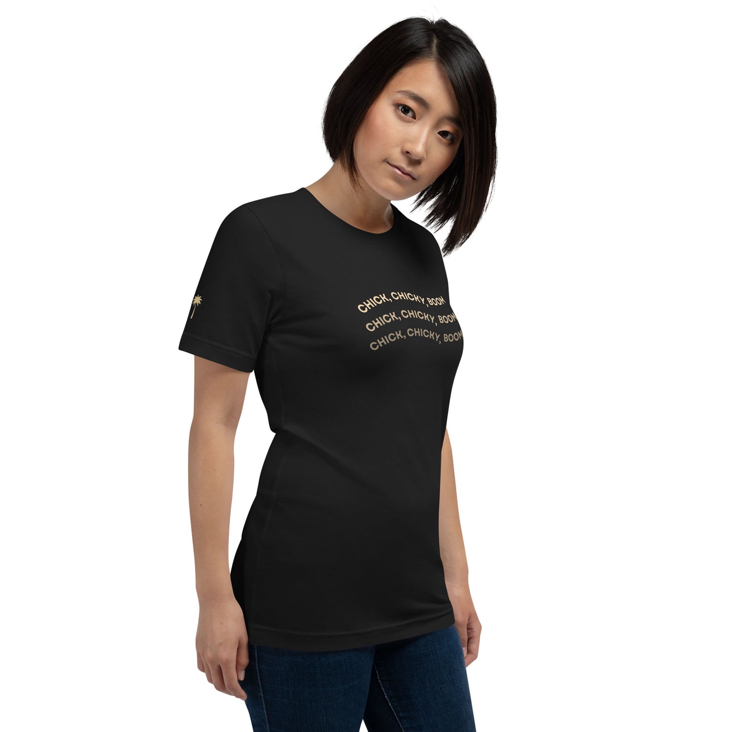 A woman with straight, shoulder-length hair wears a comfortable cotton graphic tee with gold text that reads, CHICK, CHICKY, BOOM multiple times. She stands against a plain white background, looking slightly to the side.
