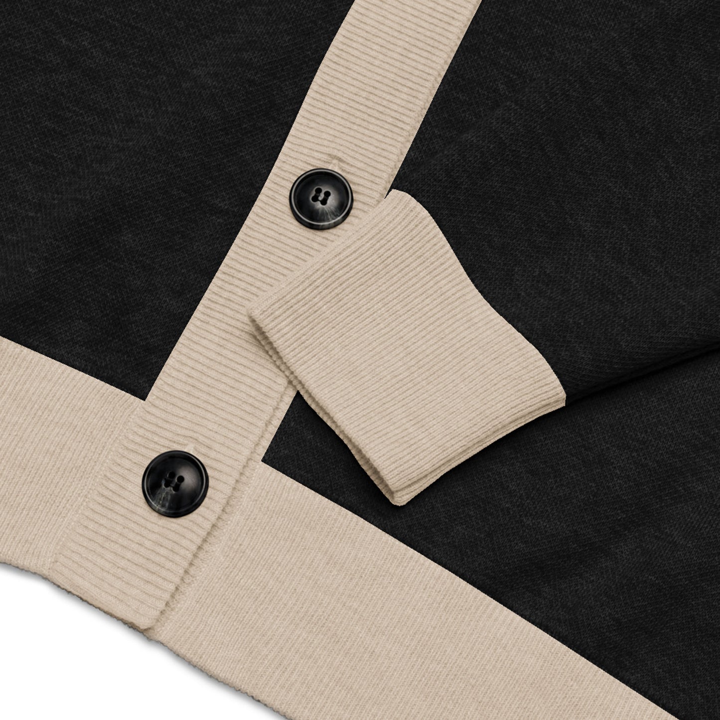 Close-up of a unisex cardigan in black fabric with beige ribbed cuffs and trim, featuring two black buttons. The sleeve is partially folded over the front of the garment.