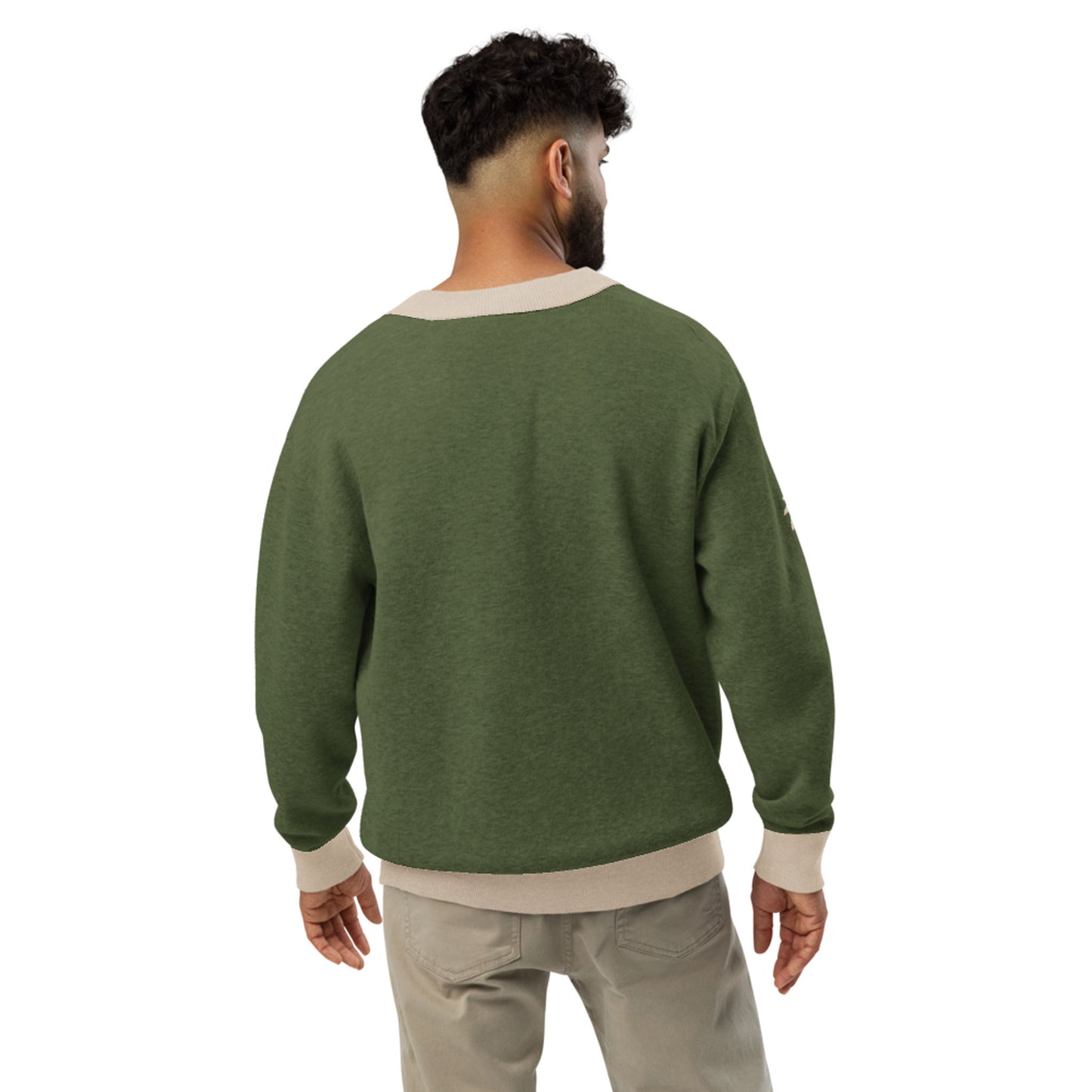 A man with short curly hair is facing away, wearing a two-tone cardigan in olive green with beige cuffs, collar, and hem, along with light beige pants, standing against a white background.