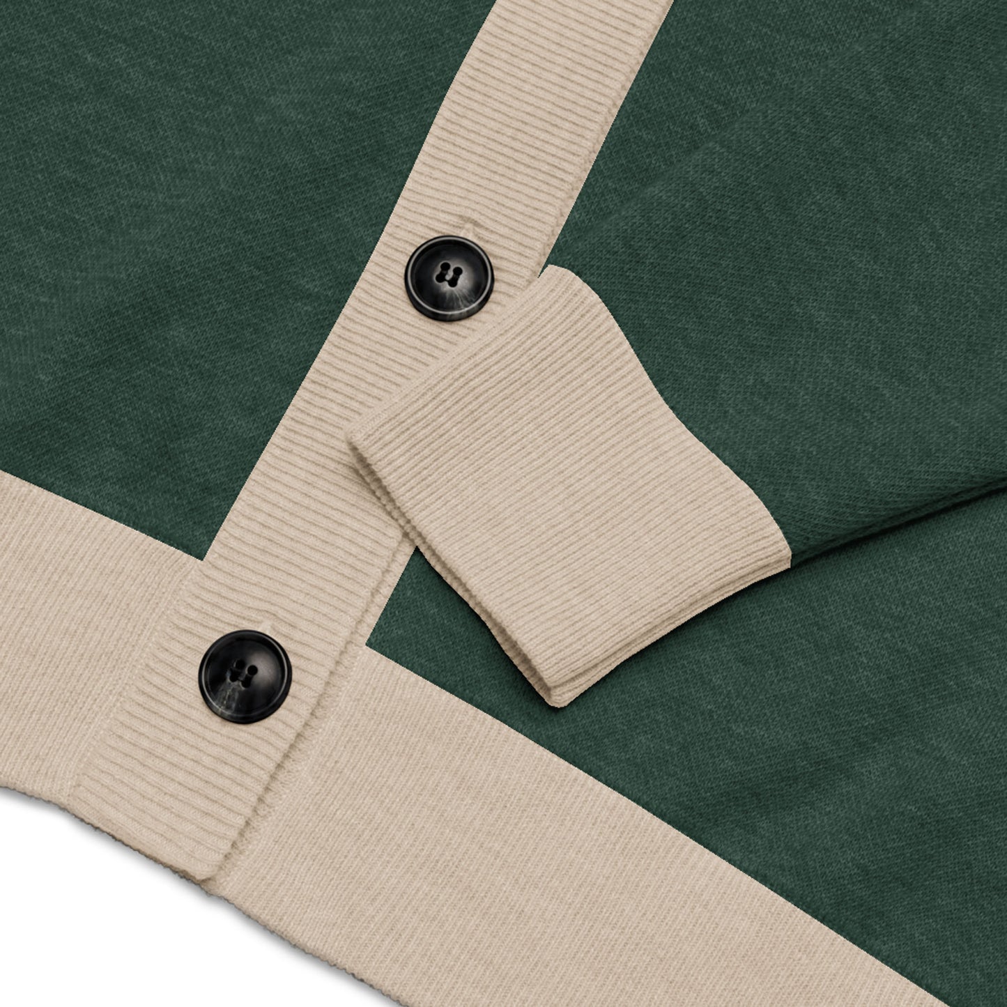 Close-up of a dark green two-tone cardigan with beige ribbed cuffs and hem, featuring two large black buttons and a folded sleeve laid across the front.