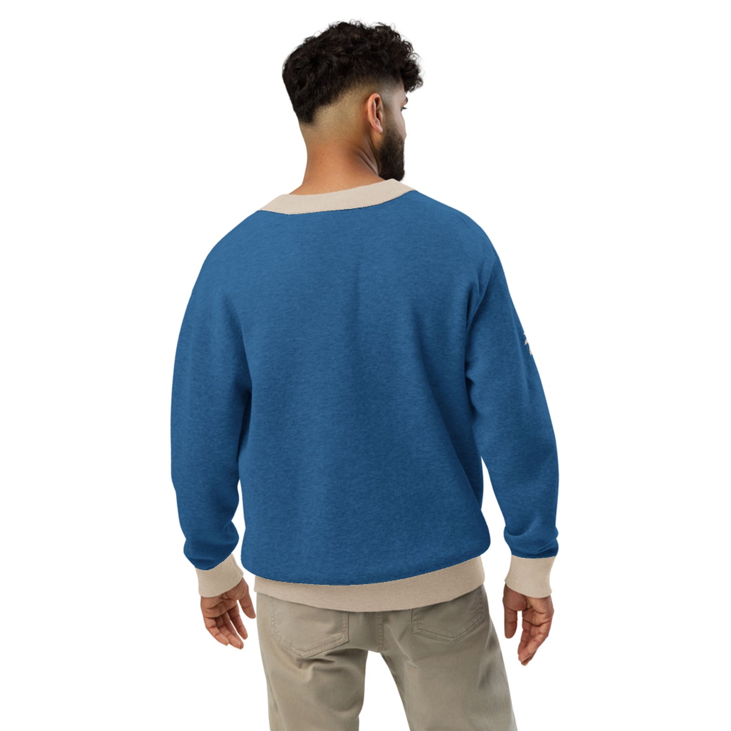 A man with short curly hair, seen from behind, wears a blue two-tone cardigan with beige cuffs and collar, paired with light-colored pants against a plain white background.