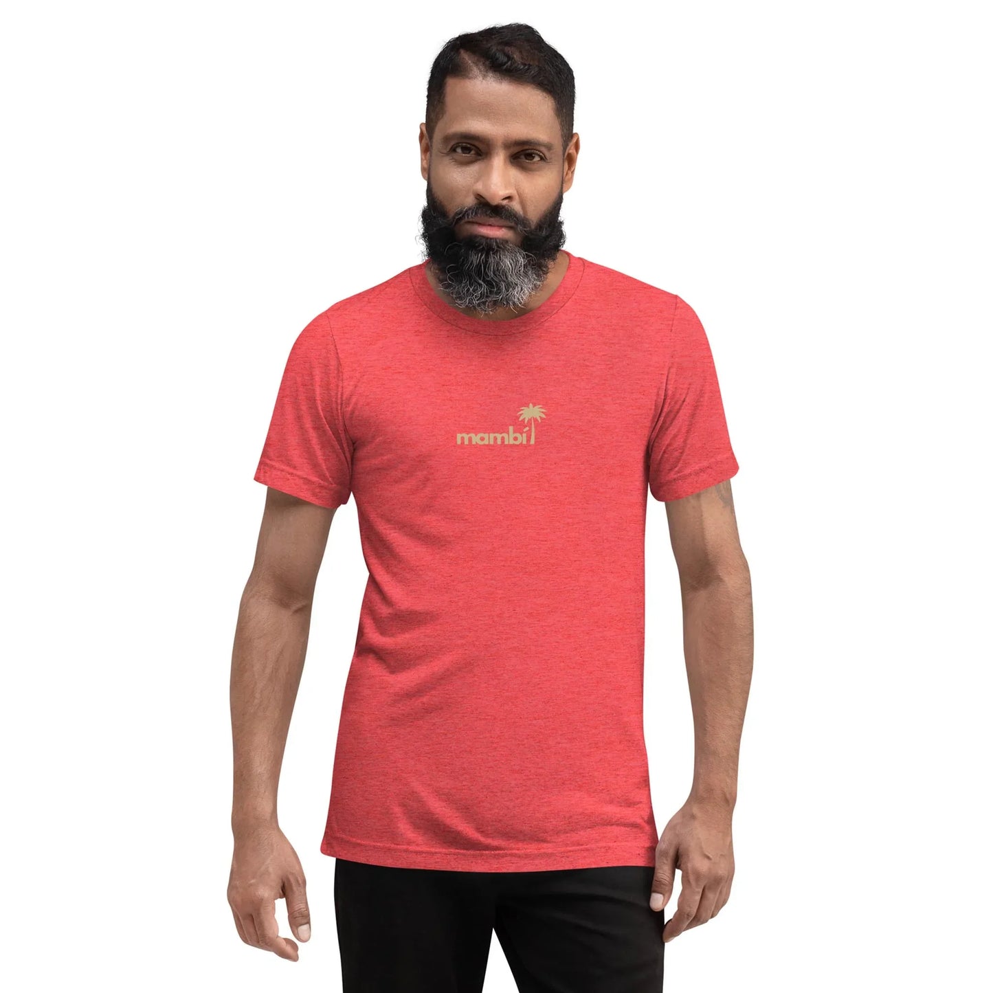 A man with a full beard and mustache models the Printful Roots Tri-Blend Graphic Tee | Unisex, a vintage-fitted red shirt featuring “mambi” and a palm tree graphic, standing against a plain white background.