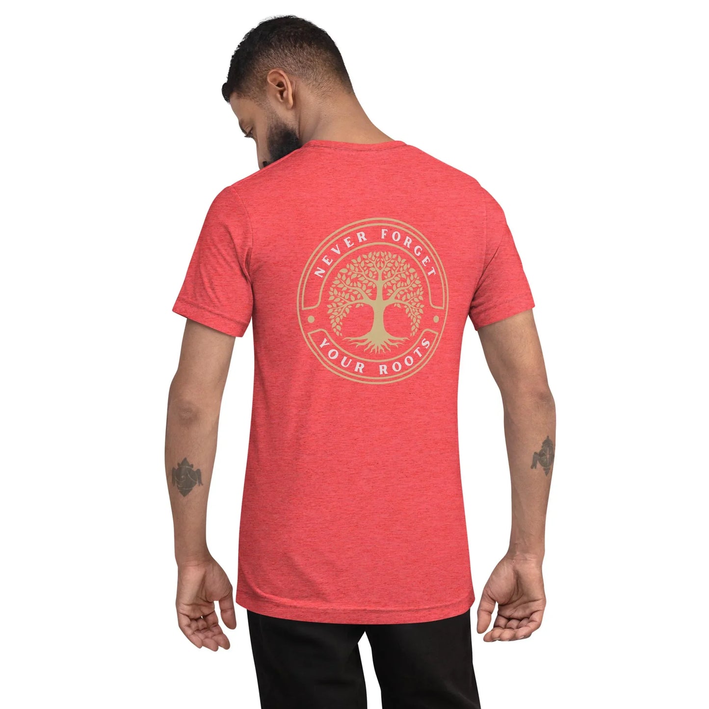 A man with short hair and tattooed forearms faces away, wearing the Printful Roots Tri-Blend Graphic Tee. The red unisex shirt features a soft tri-blend fabric, a circular tree graphic, and “Never Forget Your Roots” on the back.