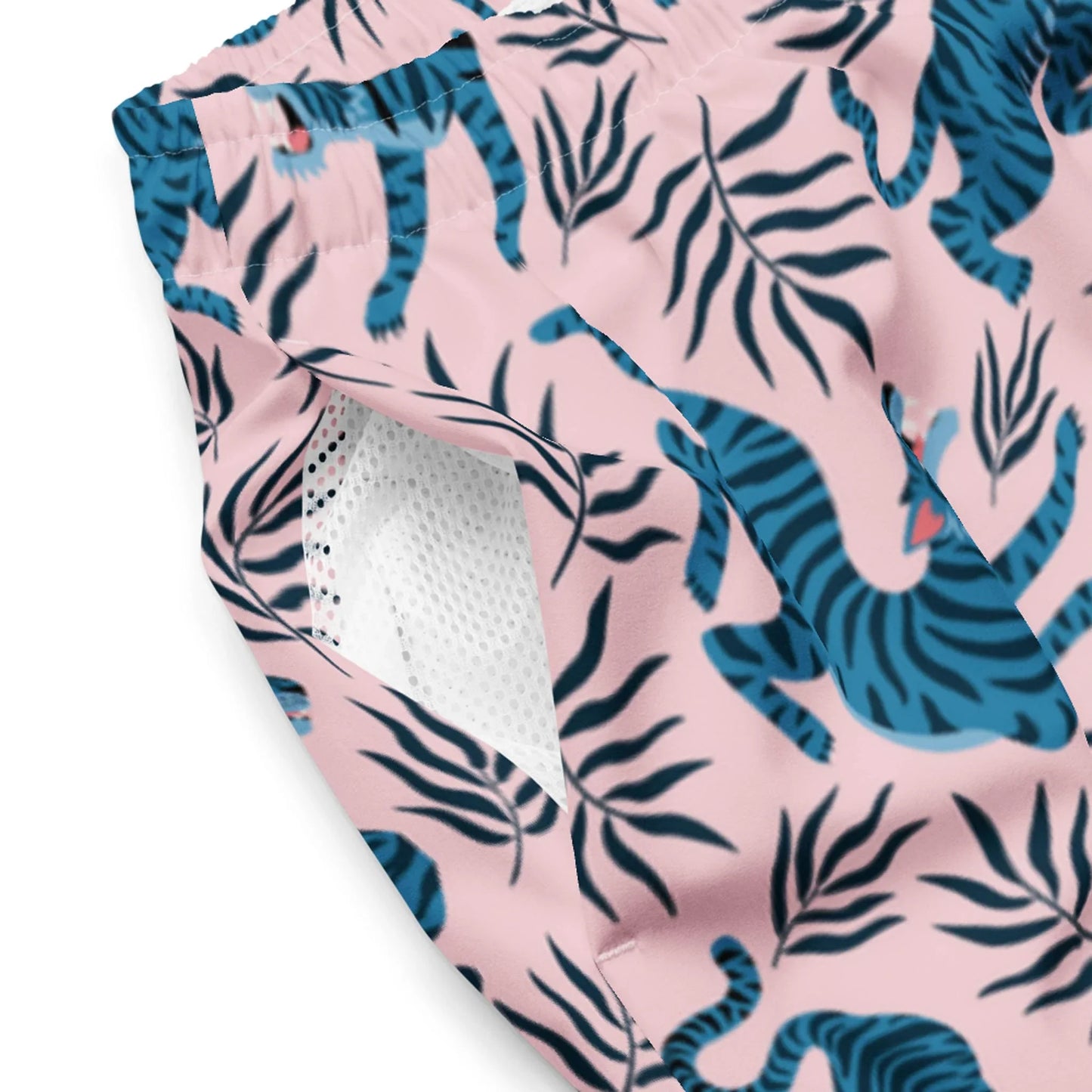 Close-up of pink athletic shorts featuring a blue tiger and black leaf pattern, inspired by Mambí style, with a visible white mesh lining inside.