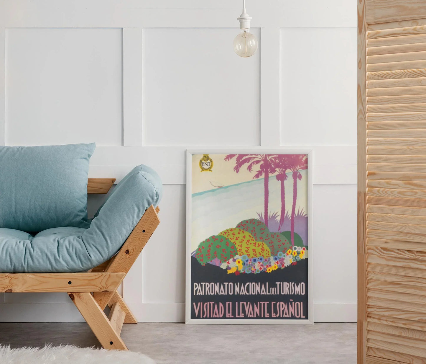 The Spanish Levant reprinted vintage poster by Printful, printed on premium luster paper (24x36), features vibrant palm trees and flowers and brings a colorful touch to a modern living room beside a blue-cushioned sofa.