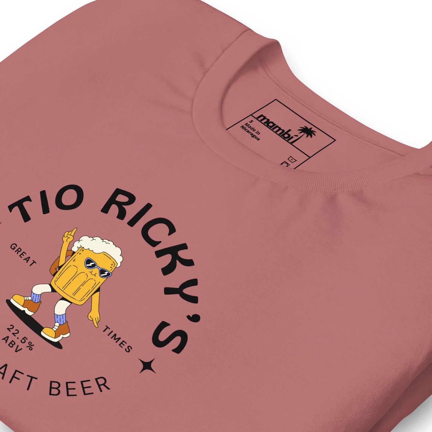 A pink t-shirt featuring a cartoon beer mug with sunglasses, arms, and legs holding up two fingers. The text reads Tio Rickys Craft Beer. Great Times. 2-8% ABV. Celebrate in Mambí style!.