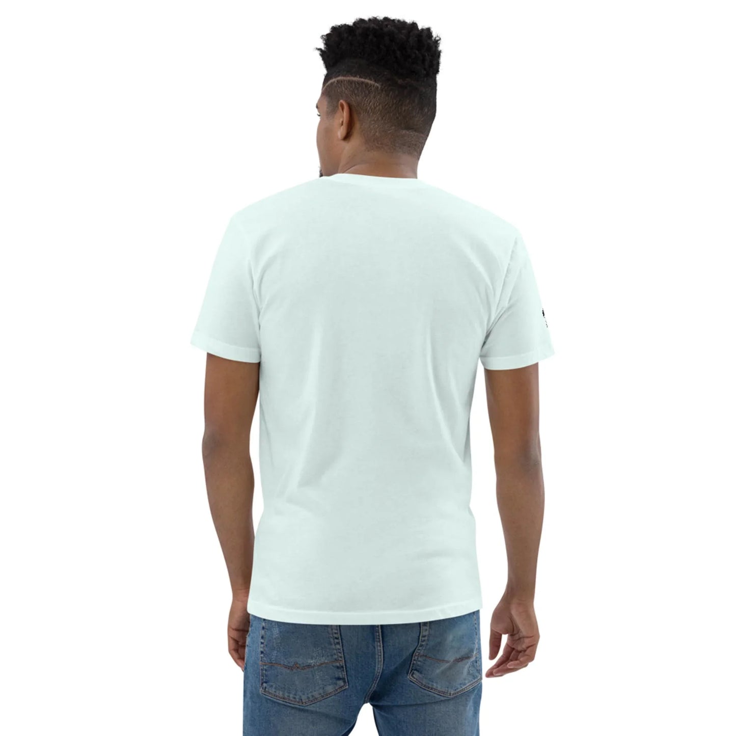 A man with short dark hair wearing a light blue Mambí T-shirt and blue jeans stands facing away, highlighting the back of the shirt.