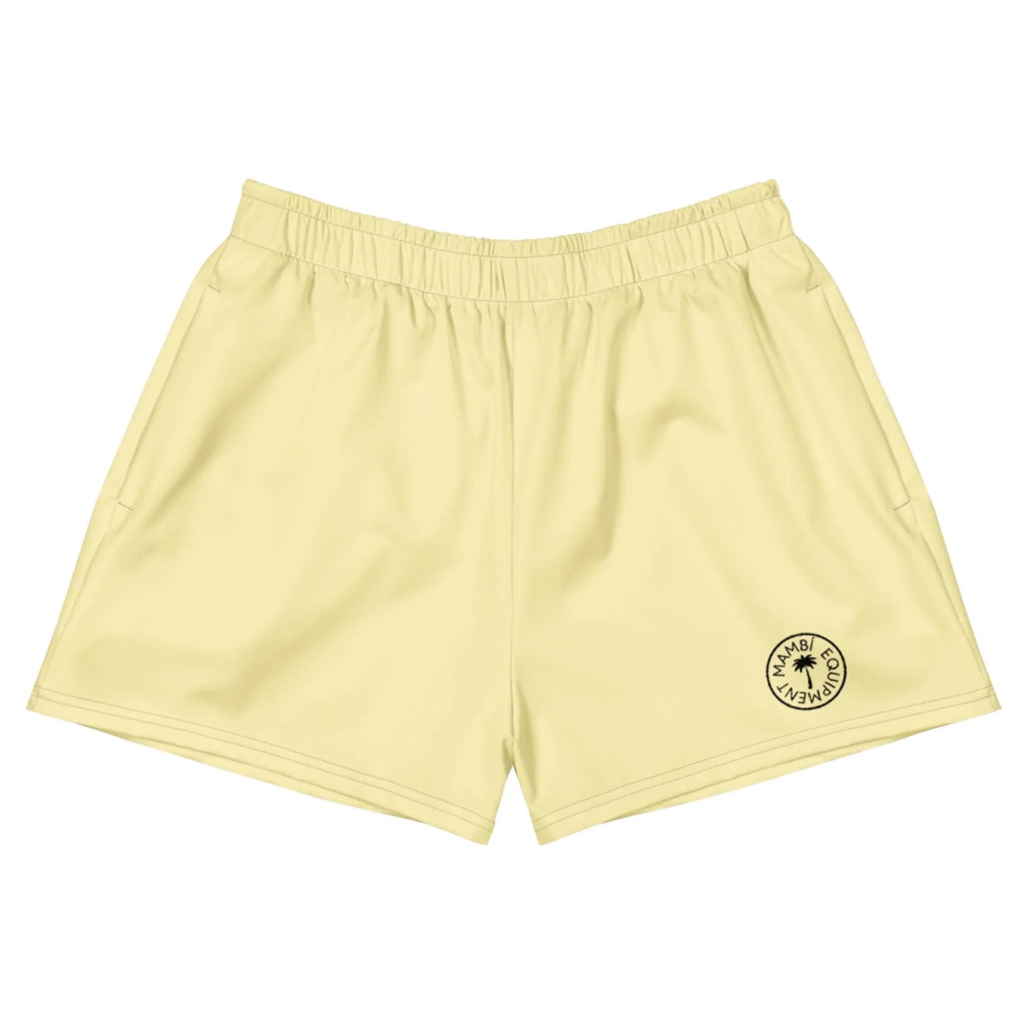 Light yellow athletic shorts with an elastic waistband and a small round black logo near the bottom left hem that reads Mambí Miami Club Wear, featuring a sun icon in the center.