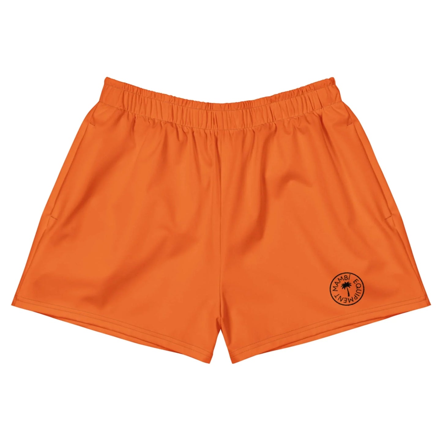 Bright orange athletic shorts with an elastic waistband. A small black circular Mambí logo with text and a star design is printed on the lower left leg. The shorts are laid flat on a white background.
