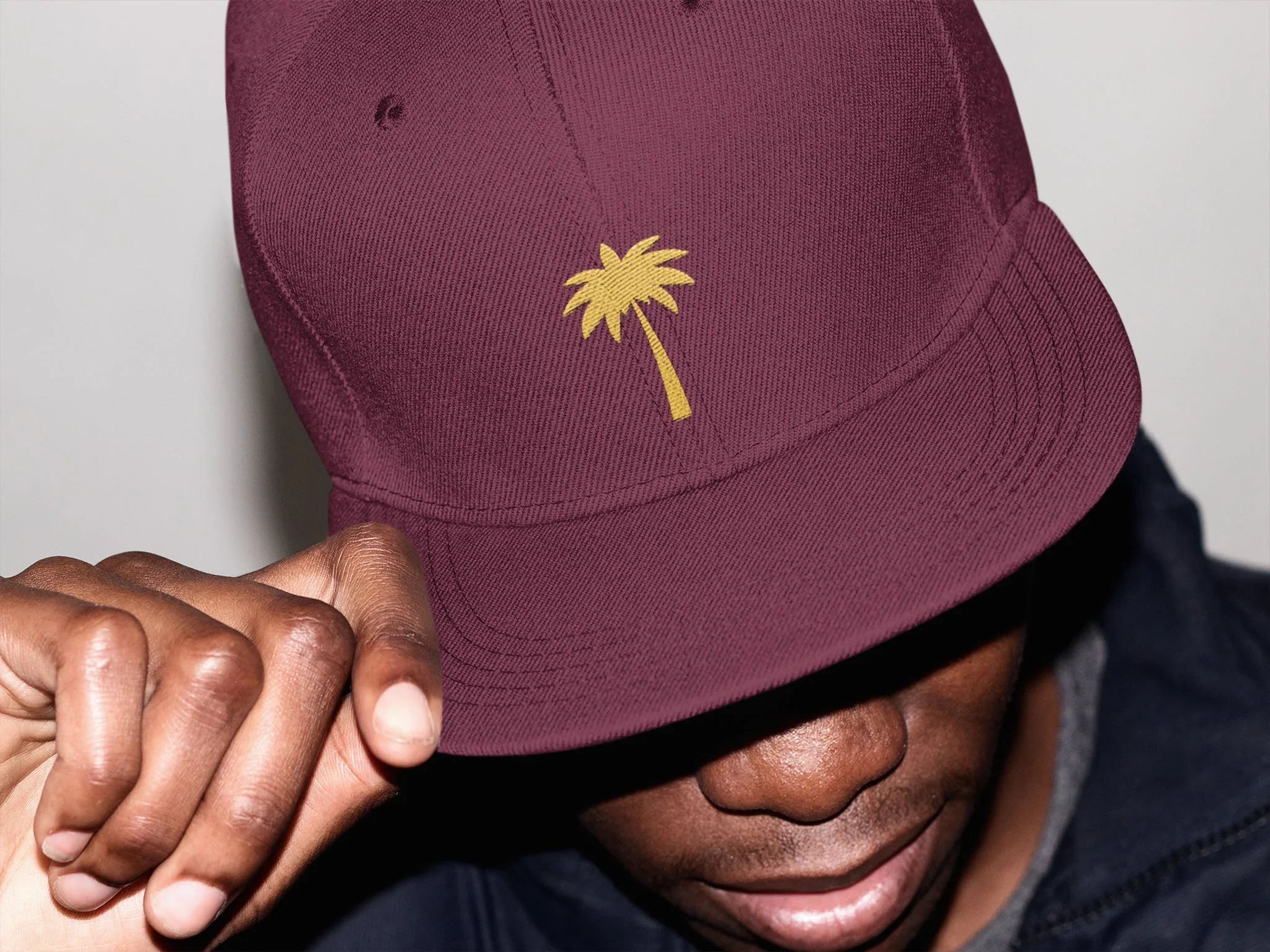 Man wearing burgundy baseball cap with yellow palm tree embroidery