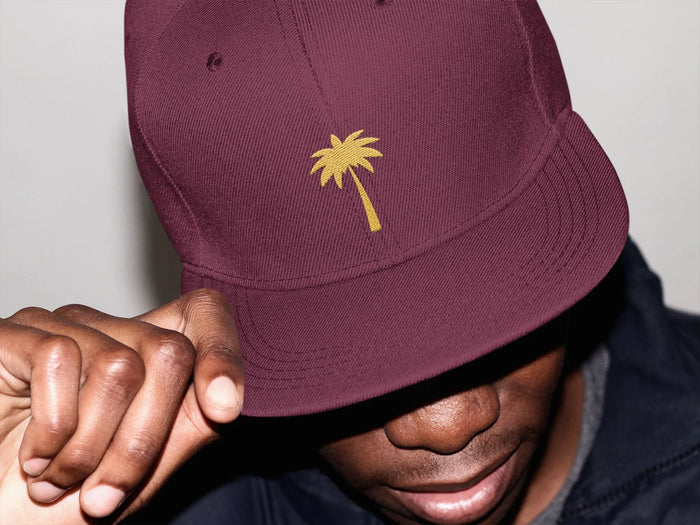 Man wearing burgundy baseball cap with yellow palm tree embroidery